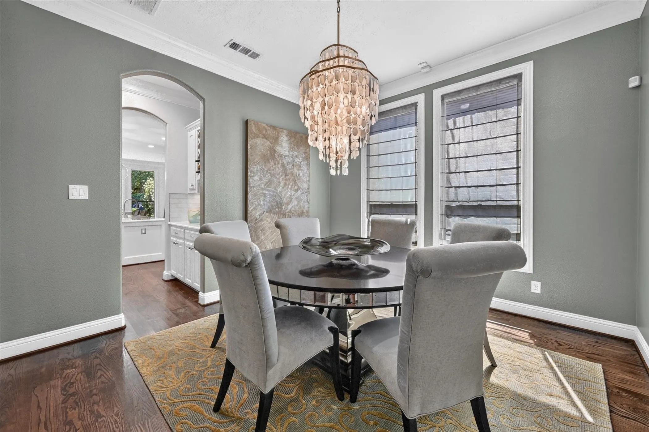 Formal dining area featuring hardwood flooring, crown molding, and an arched entryway