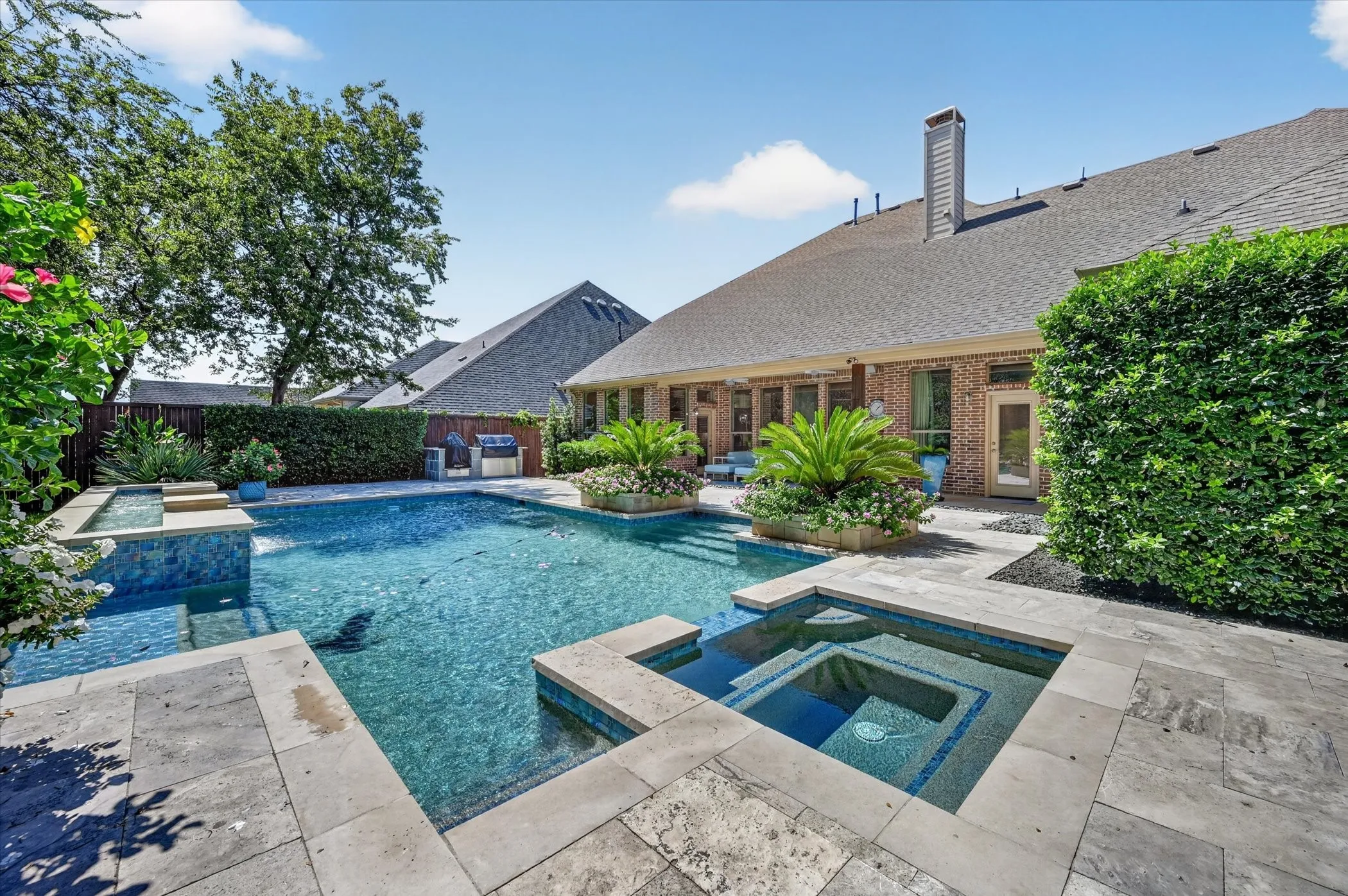 Outdoor pool with integrated spa and stone coping