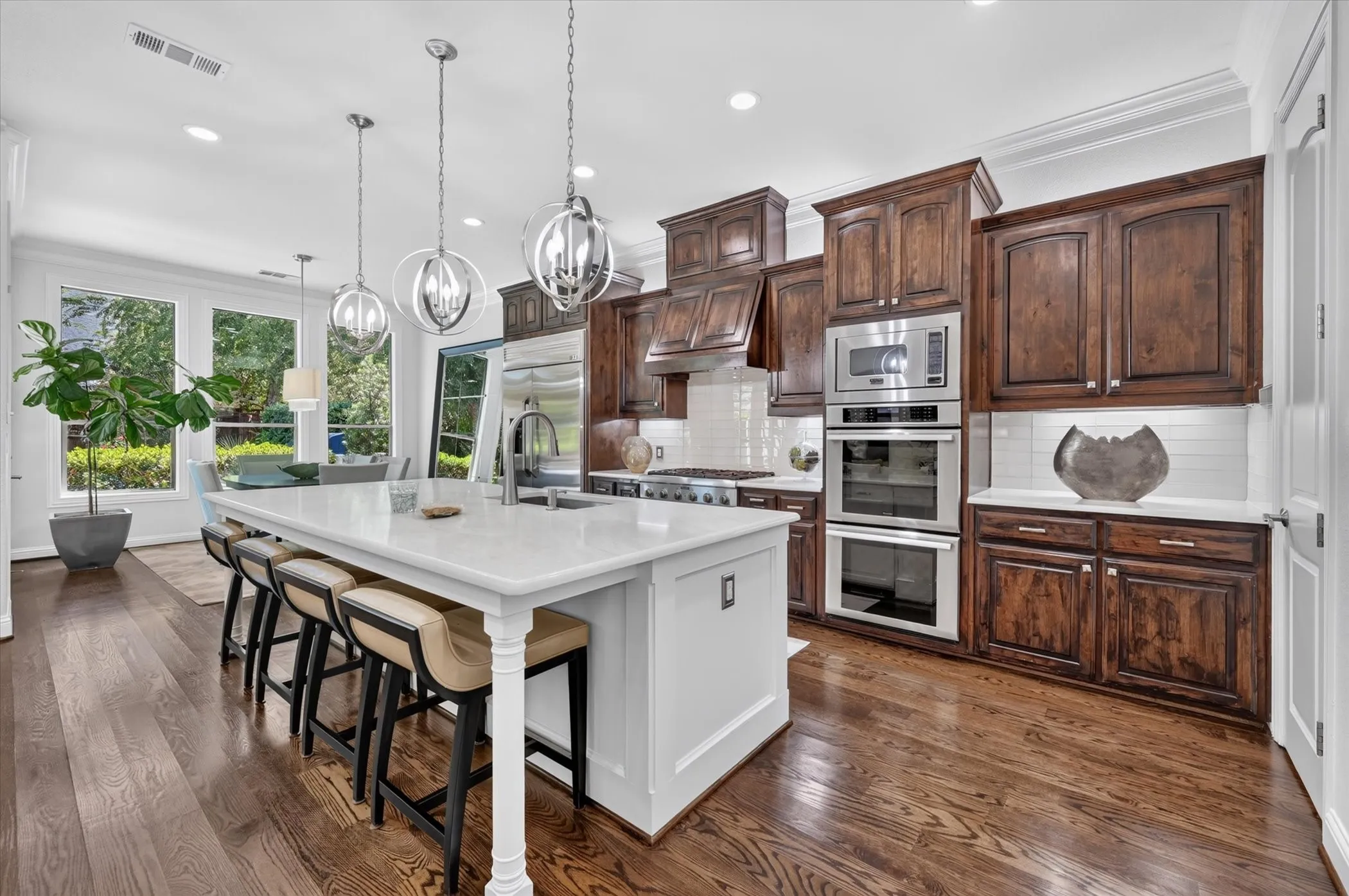 Kitchen featuring a large island with a light-toned countertop, dark wood-finish cabinetry, stainless steel appliances, recessed lighting, and wood-finish flooring