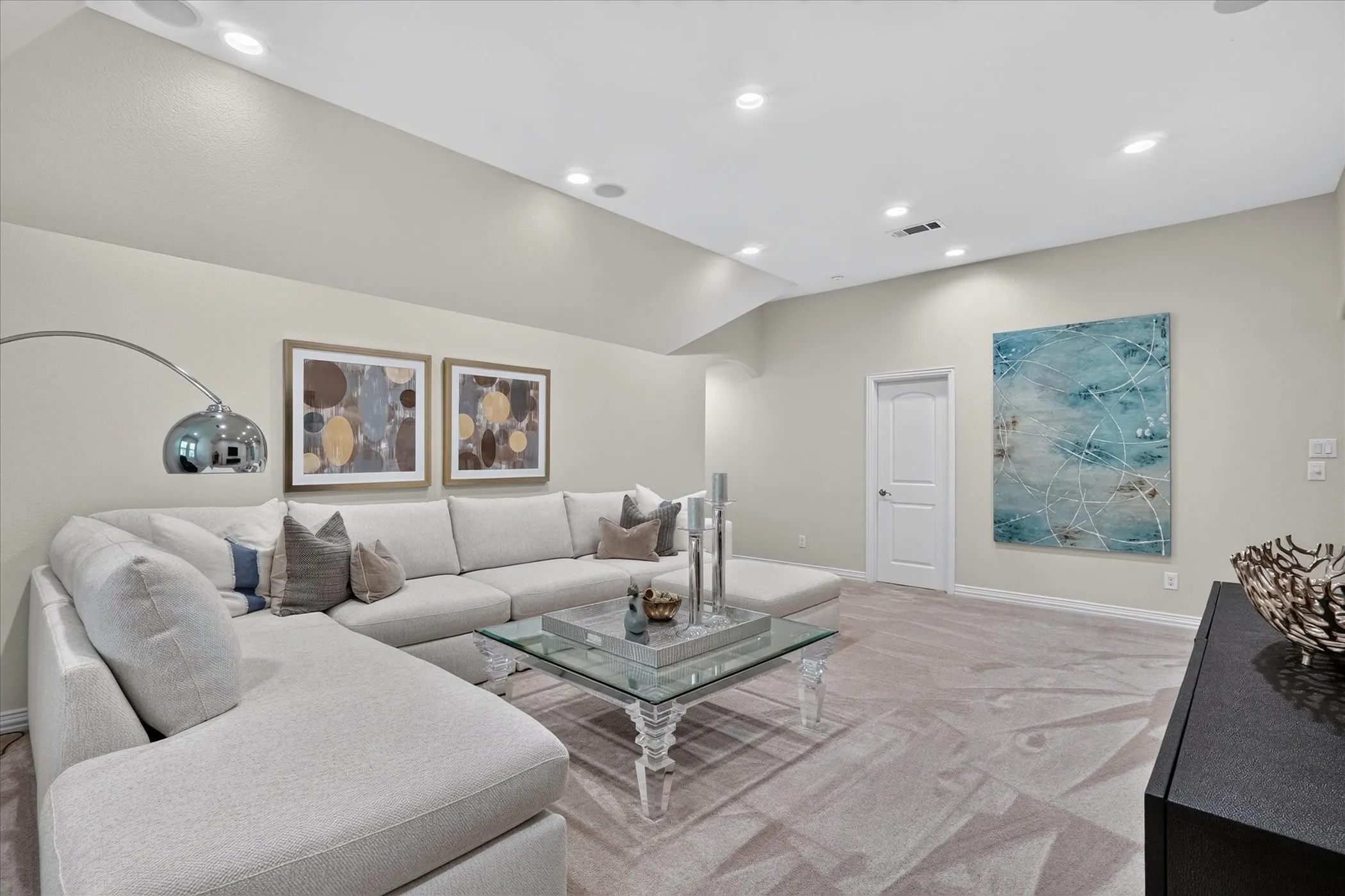 Recessed lighting illuminates neutral-toned walls and a light-colored carpet
