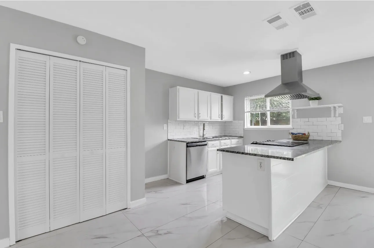 Kitchen featuring a central island with a built-in cooktop, stainless steel range hood, white cabinetry, and a subway tile backsplash