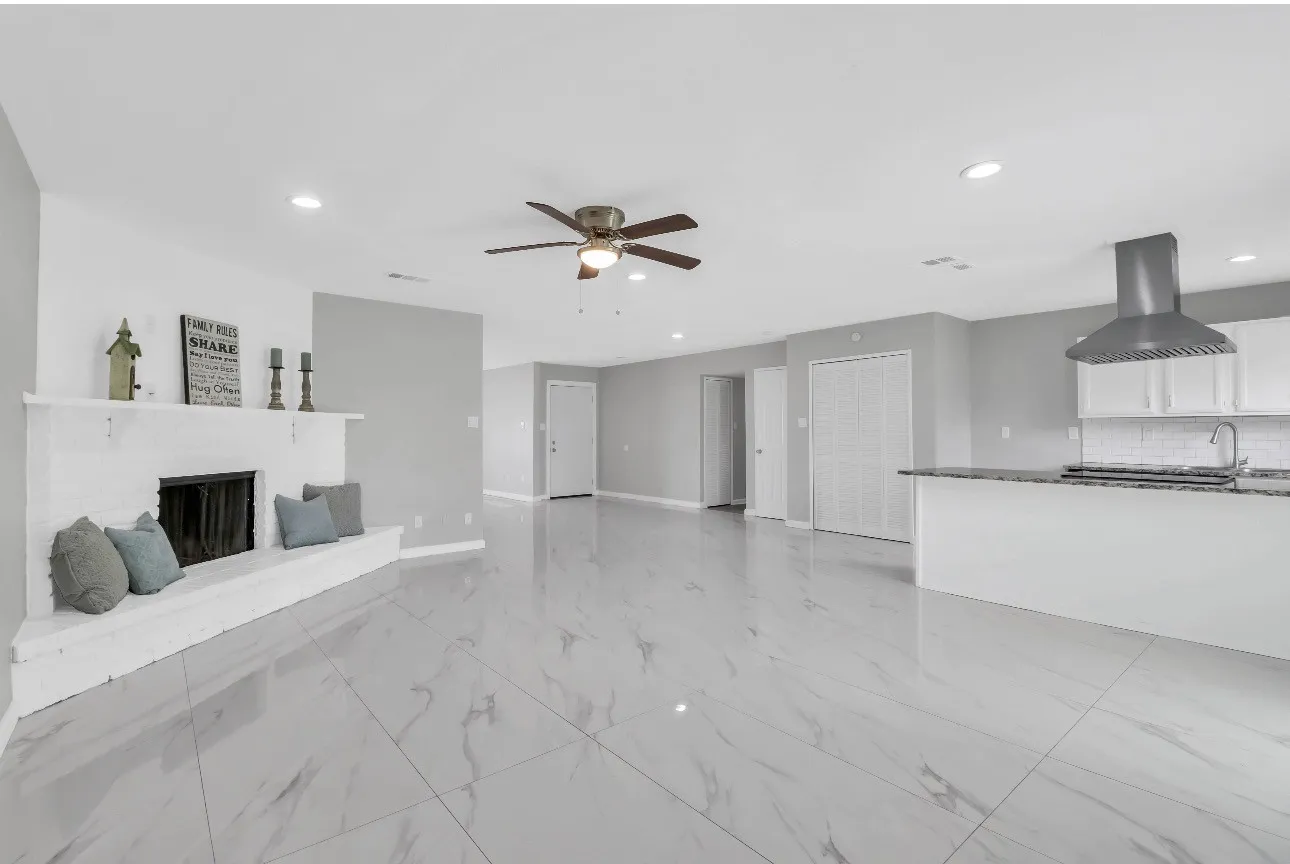 Spacious interior with large format tile flooring and a white brick fireplace