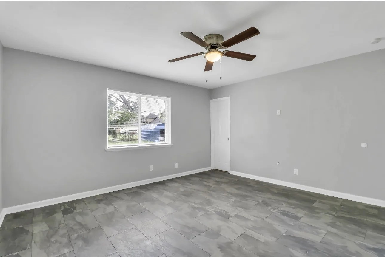 Spacious room featuring gray walls, wood-finish flooring, and white baseboards