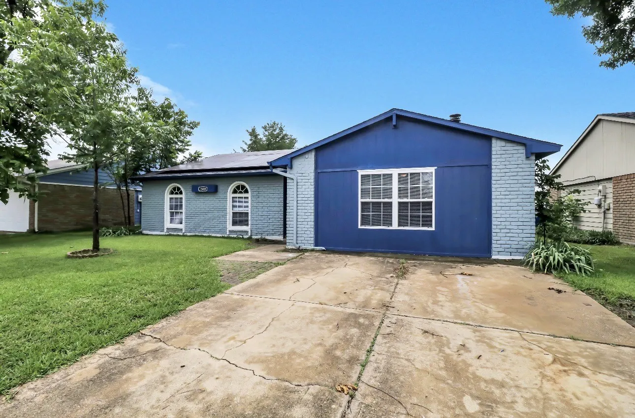 Blue exterior with white trim, featuring a concrete driveway and a manicured green lawn