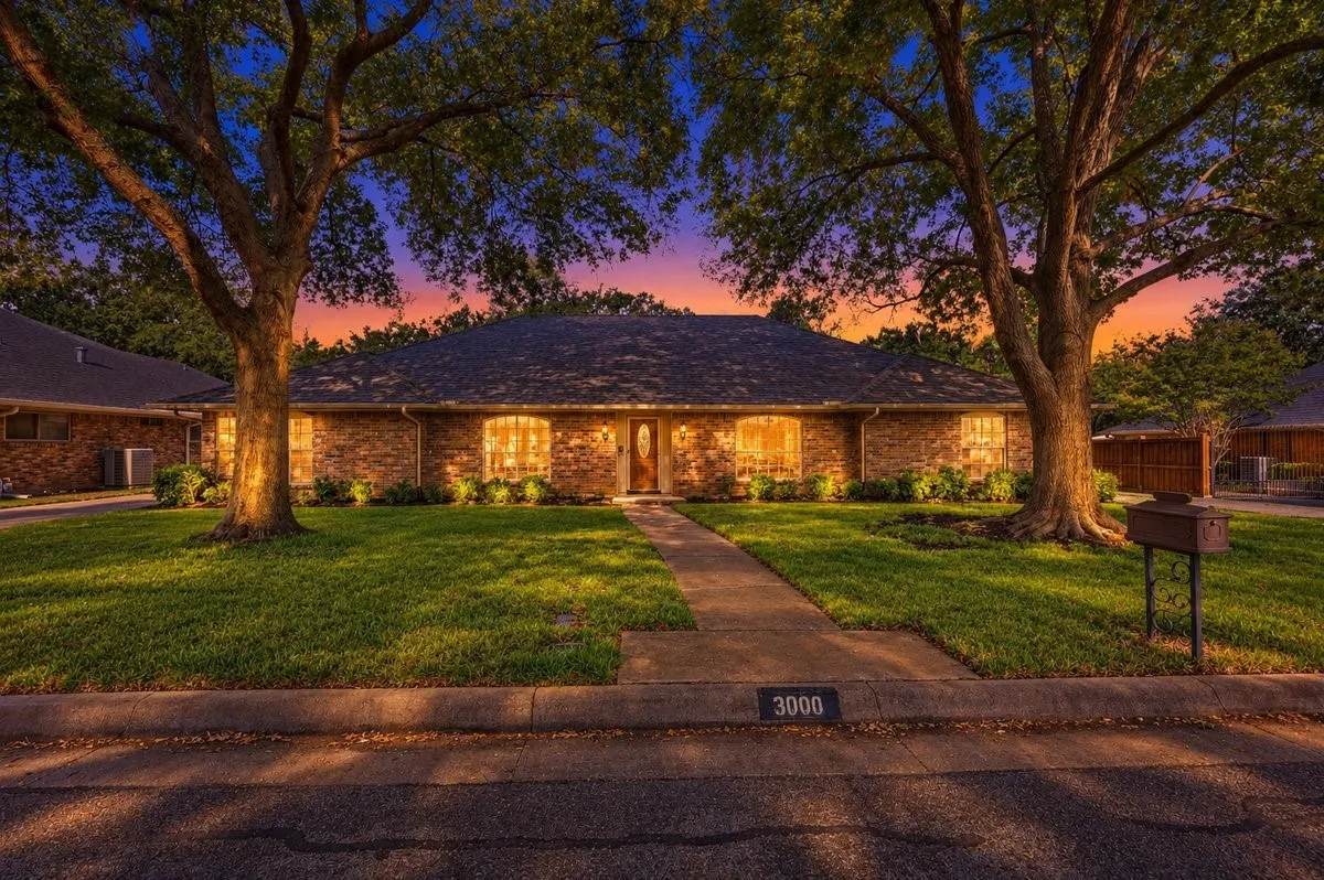 Brick exterior with a dark shingle roof, arched windows, and a wood-finish front door