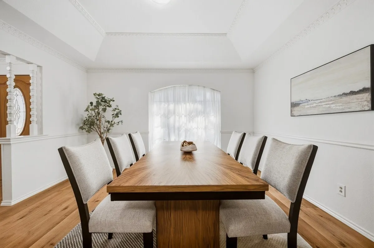 Wood-finish flooring, white walls with wainscoting, and a decorative tray ceiling
