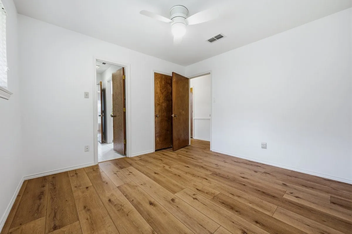 Spacious room featuring wood-finish flooring and a ceiling fan
