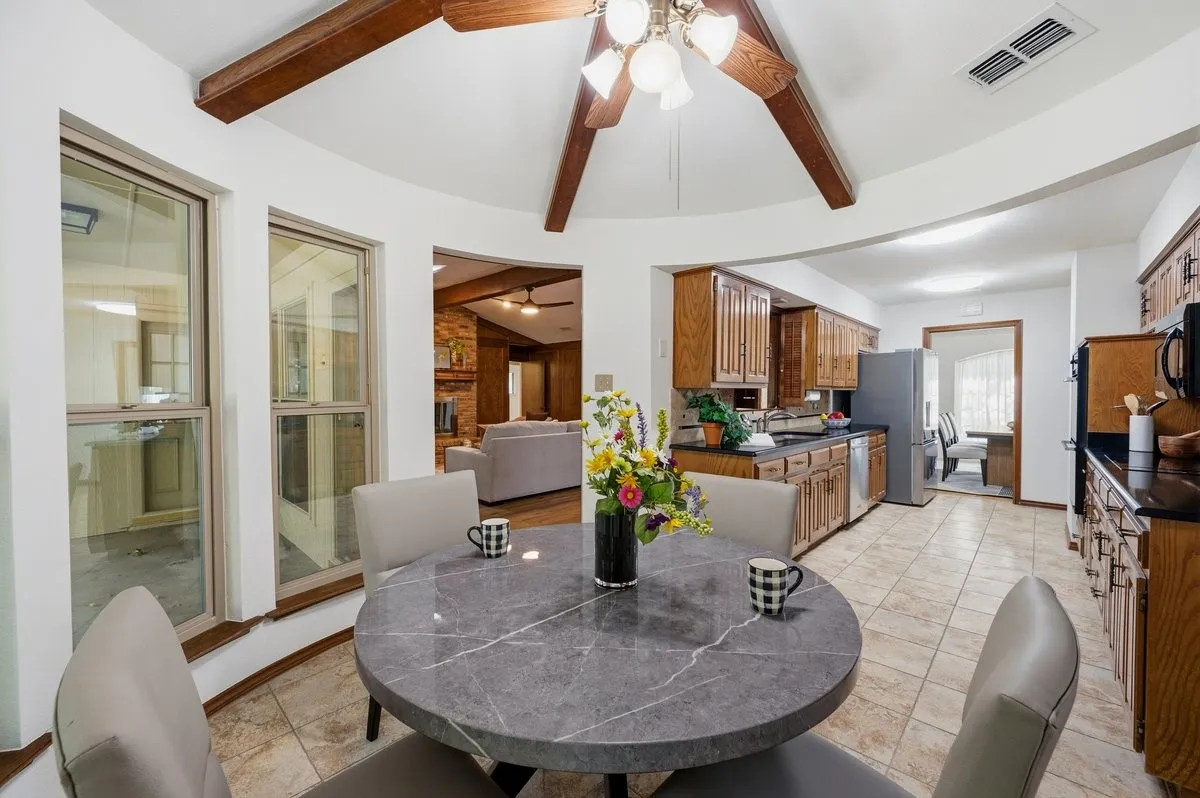 Kitchen with wood cabinetry, black countertops, and tile flooring