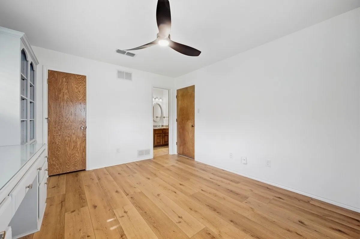Wood-finish flooring, white walls, and a ceiling fan with integrated lighting