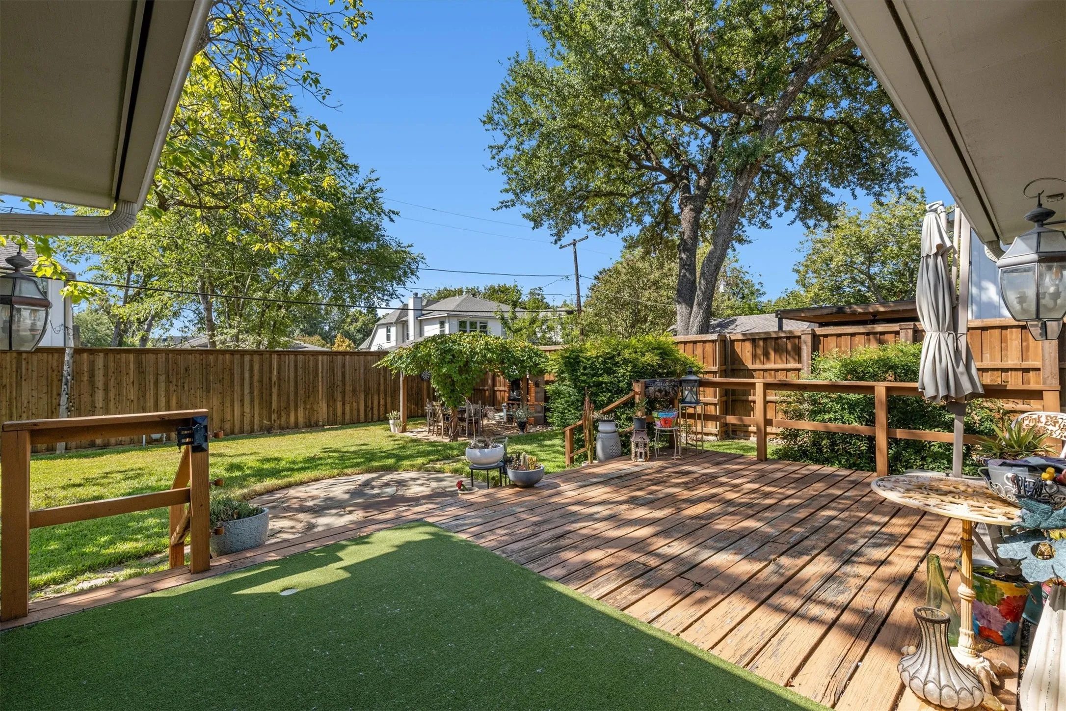 Expansive backyard featuring a wood deck, artificial turf, natural grass, and privacy fencing