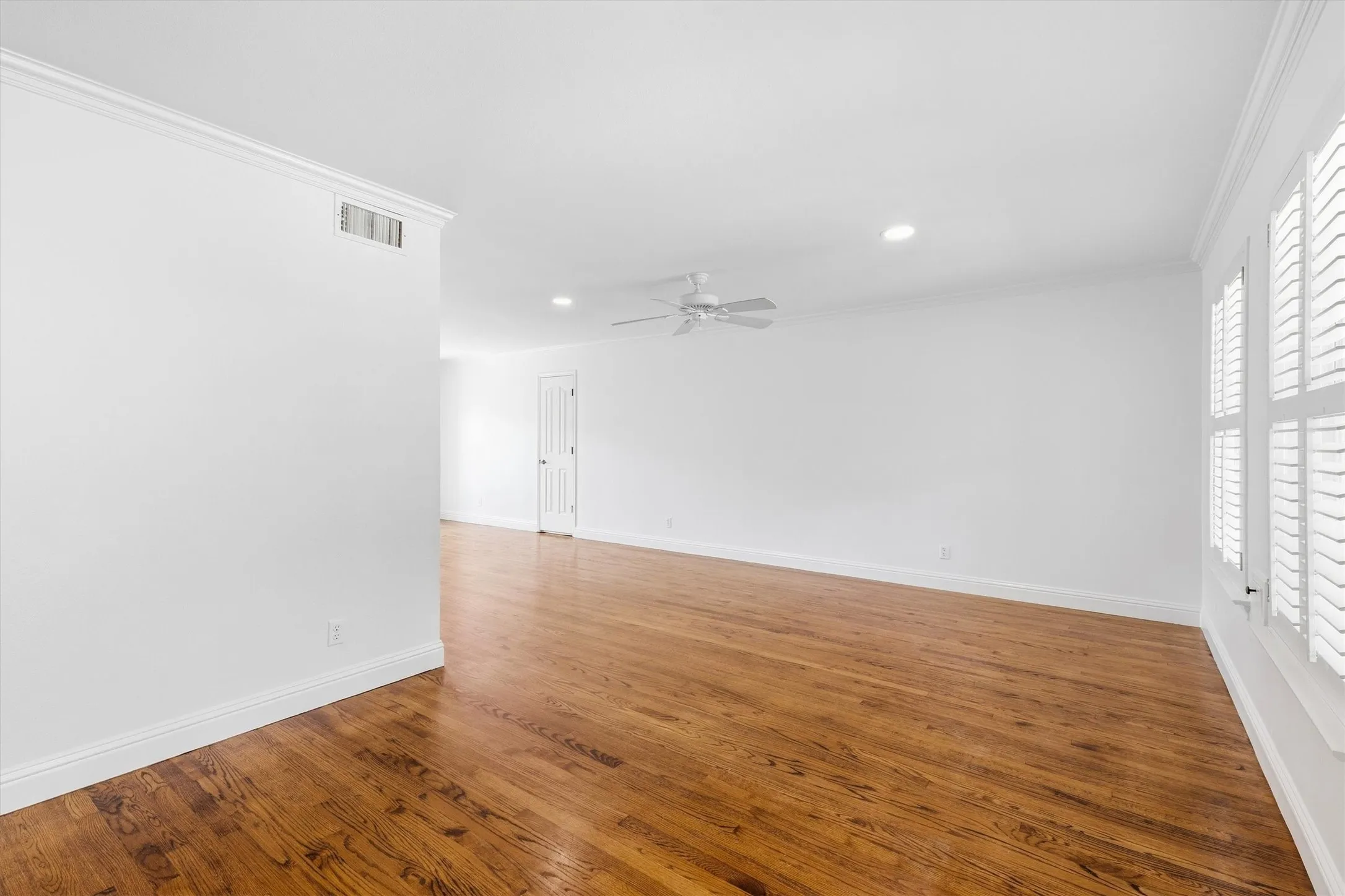 Hardwood flooring, plantation shutters, crown molding, recessed lighting, and a ceiling fan