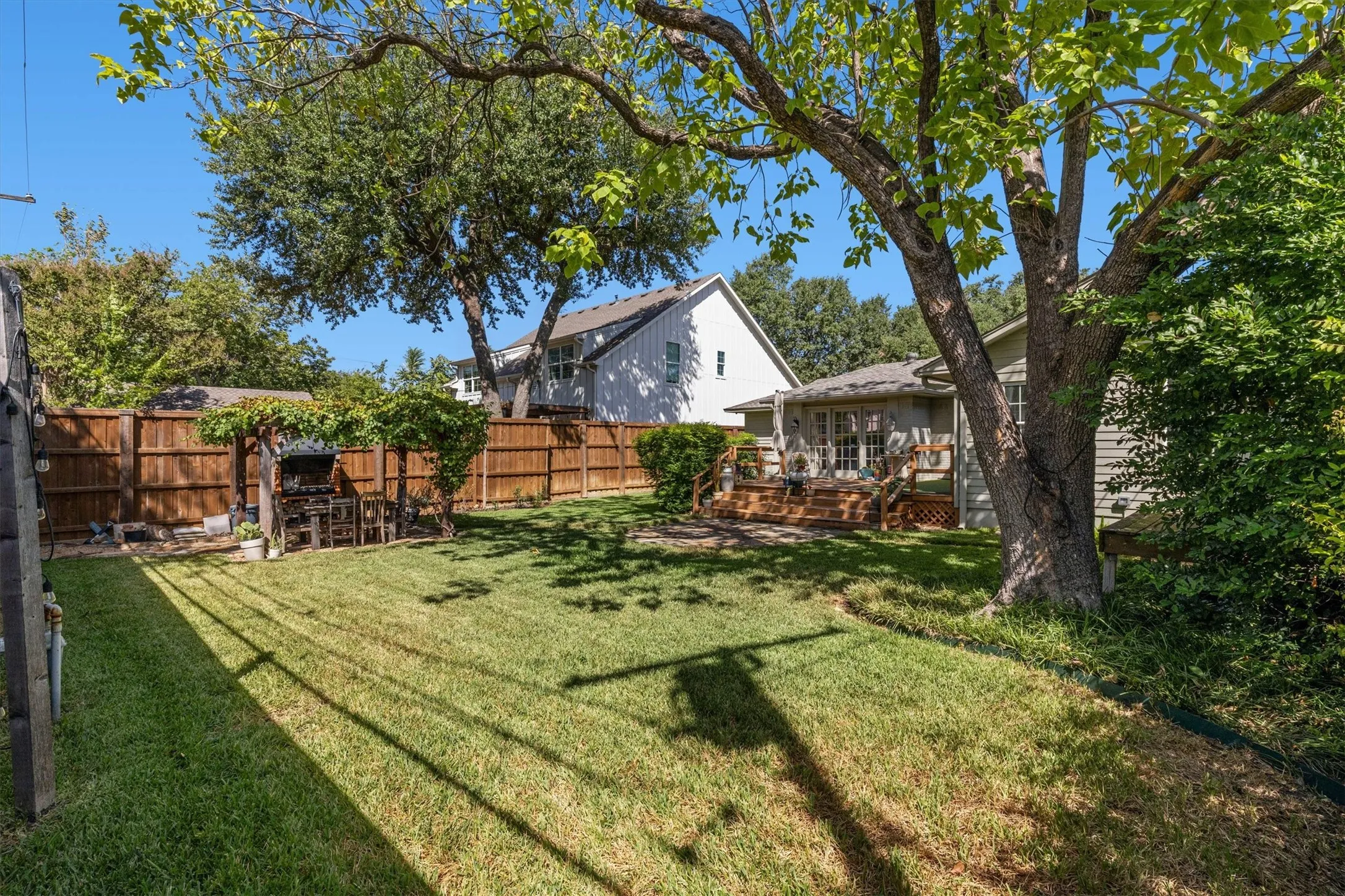 Expansive lawn area, complete wood privacy fencing, mature trees, and a built-in outdoor cooking station