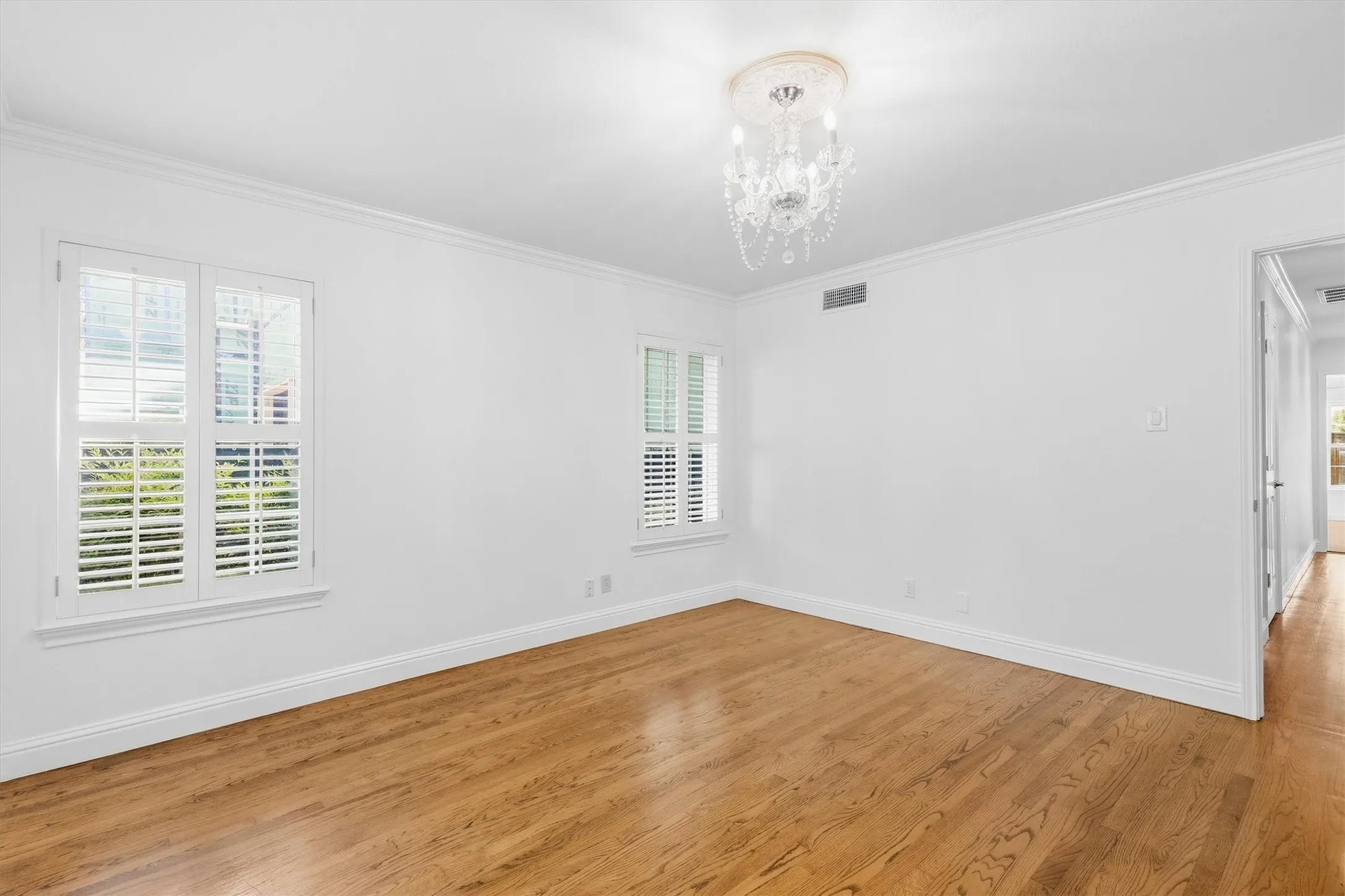 Wood-finish flooring, white walls, and crown molding