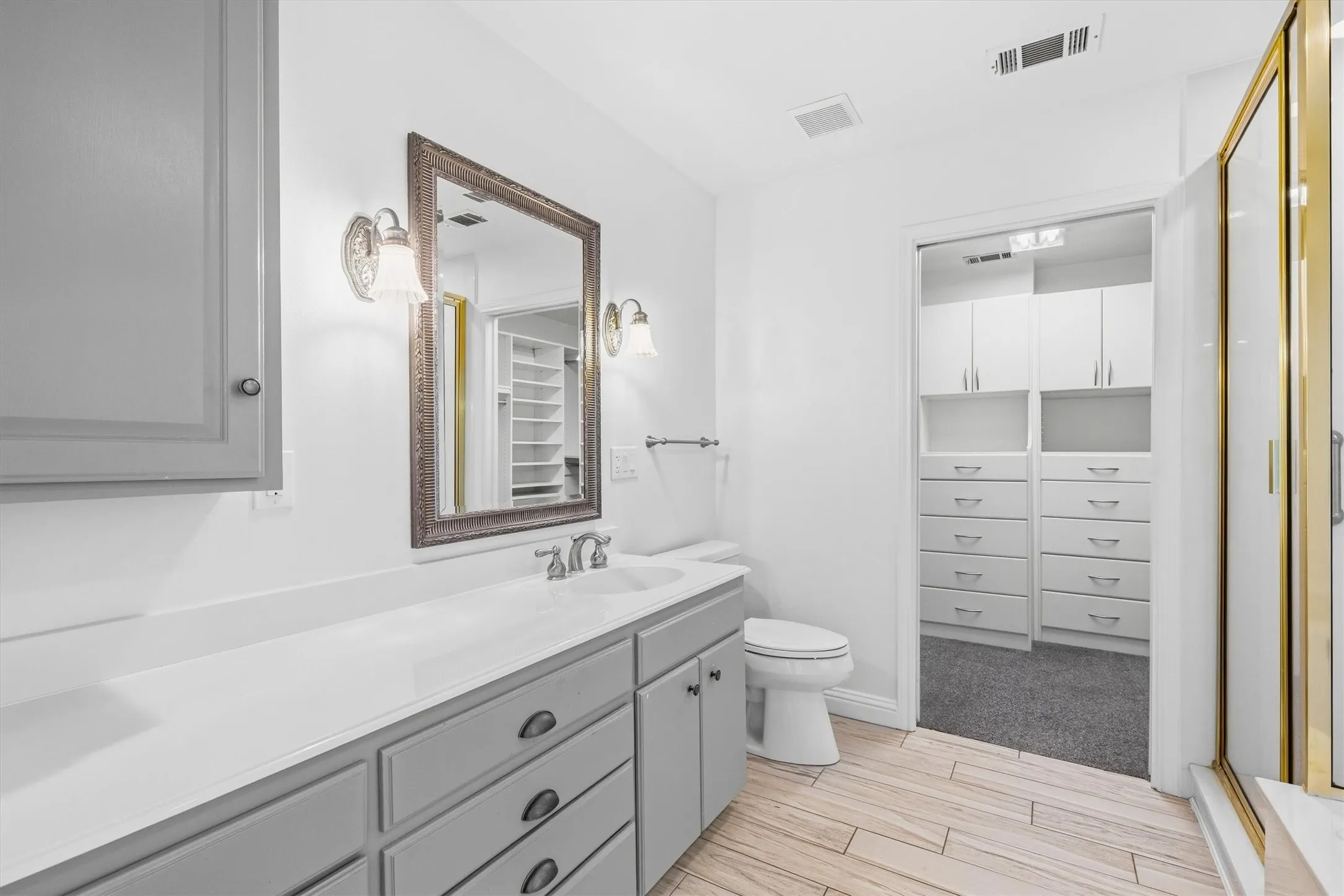 Bathroom featuring a vanity with an integrated sink, framed mirror, and two wall sconces