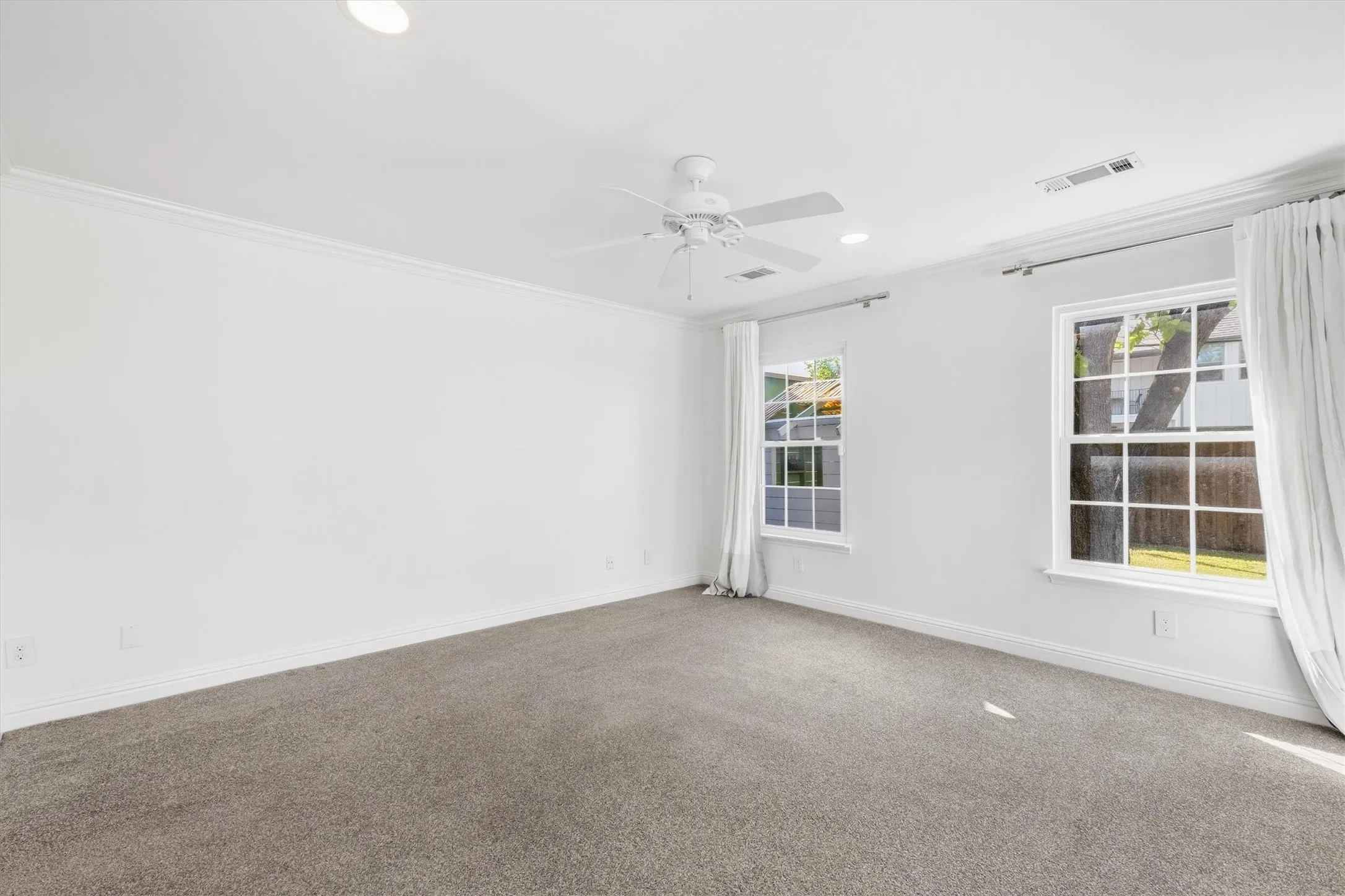 Recessed ceiling lighting, crown molding, double pane windows, ceiling fan, and gray carpeting