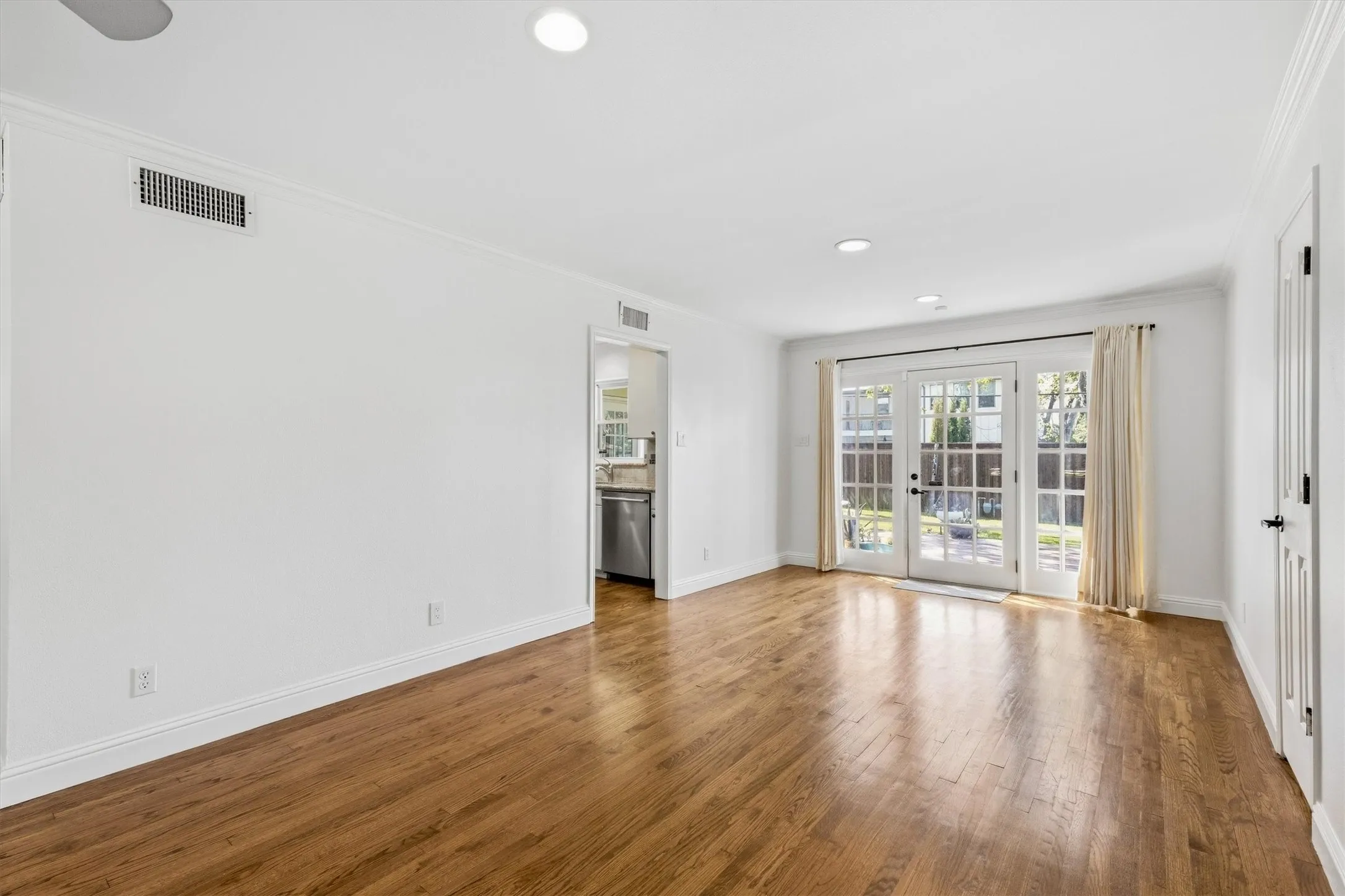 Hardwood flooring throughout, white walls, recessed lighting, and French doors leading to exterior