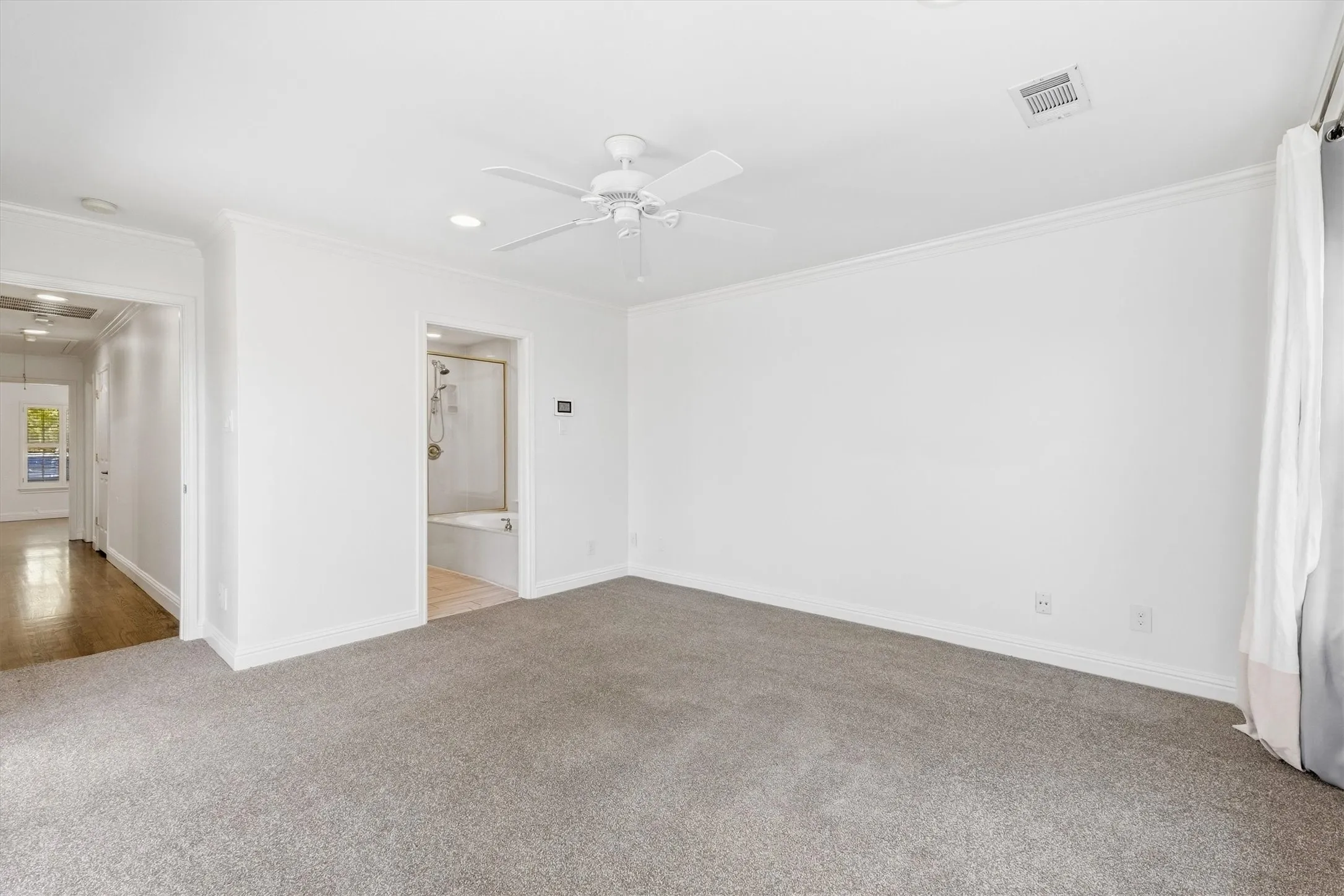 Spacious interior featuring neutral carpet, crown molding, a ceiling fan, and recessed lighting