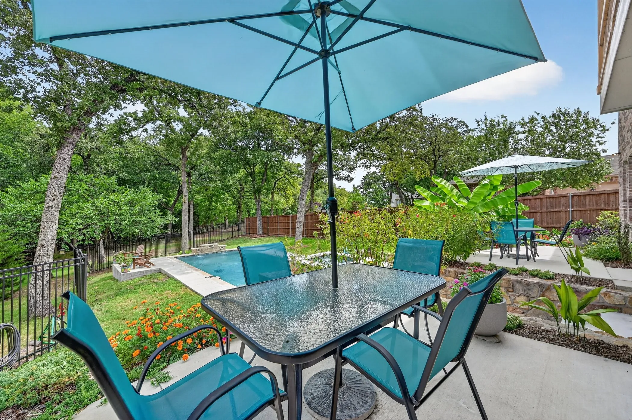 Patio featuring a concrete surface, stone retaining wall, and mature landscaping