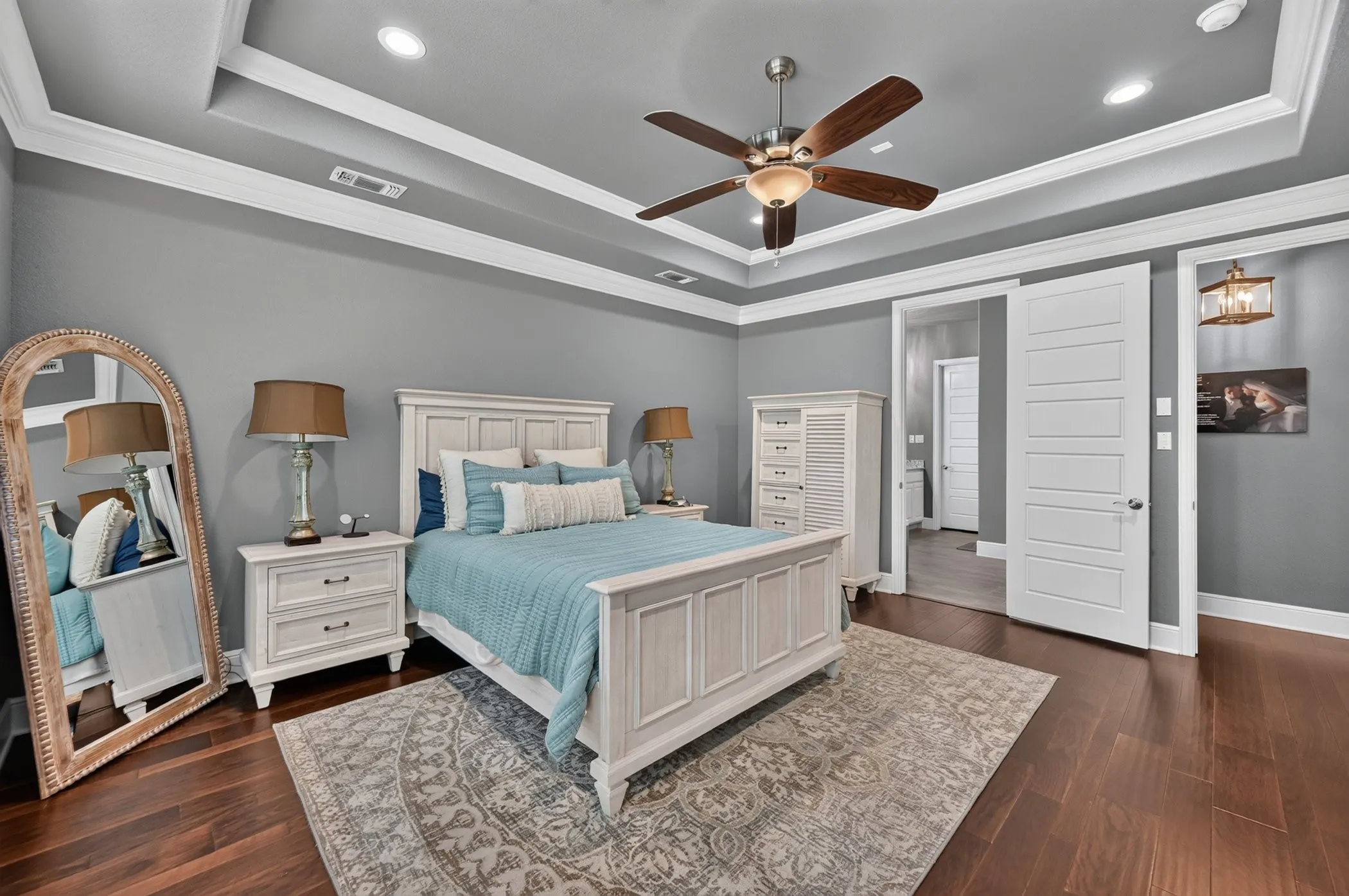 Tray ceiling with crown molding, recessed lighting, wood flooring, and a ceiling fan