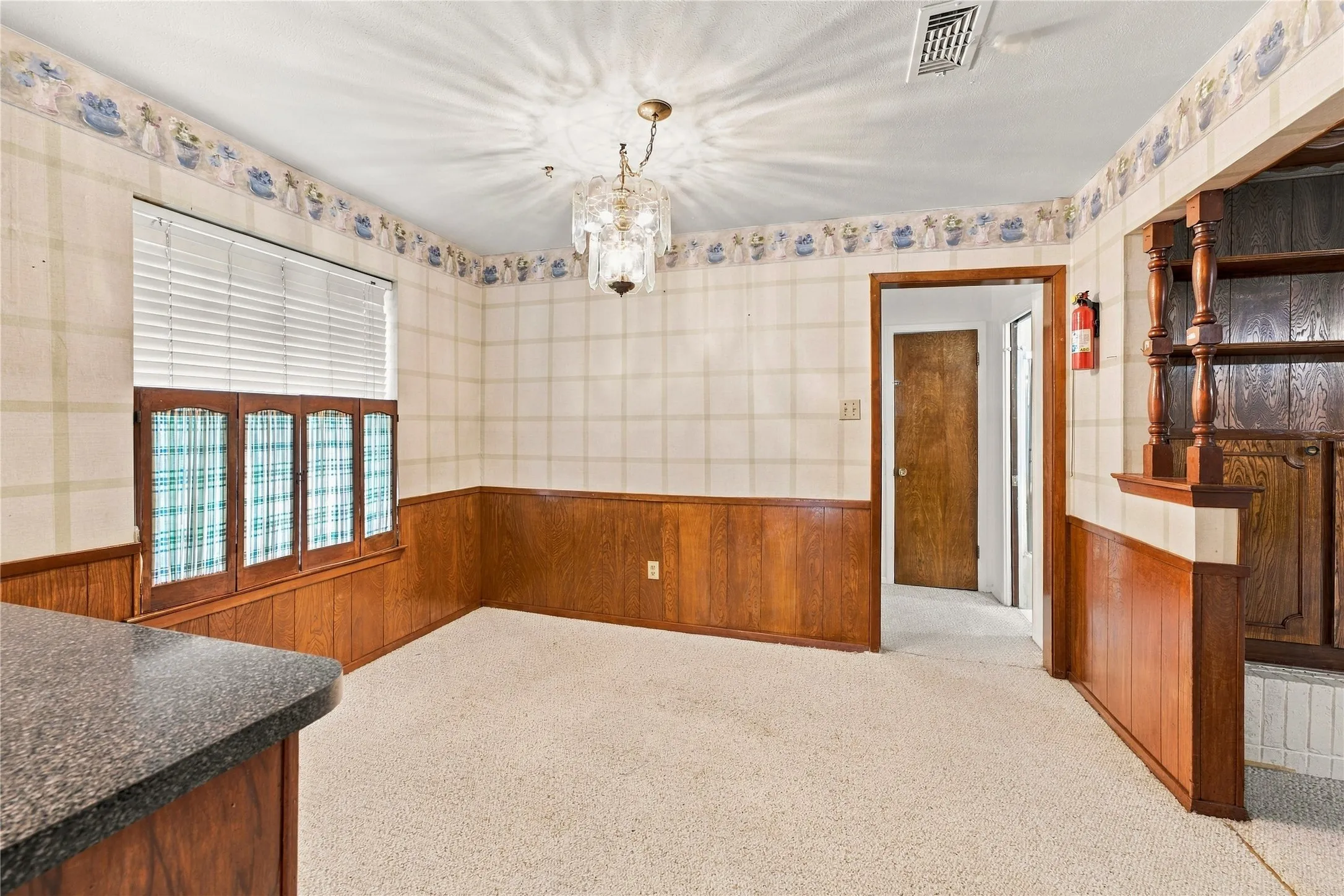 Carpeted flooring, wood paneling, decorative wallpaper, and a built-in chandelier