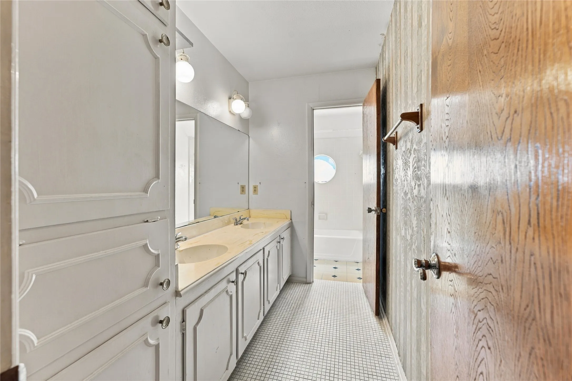 Dual vanity with built-in sinks, white cabinetry, a large wall mirror, and overhead lighting