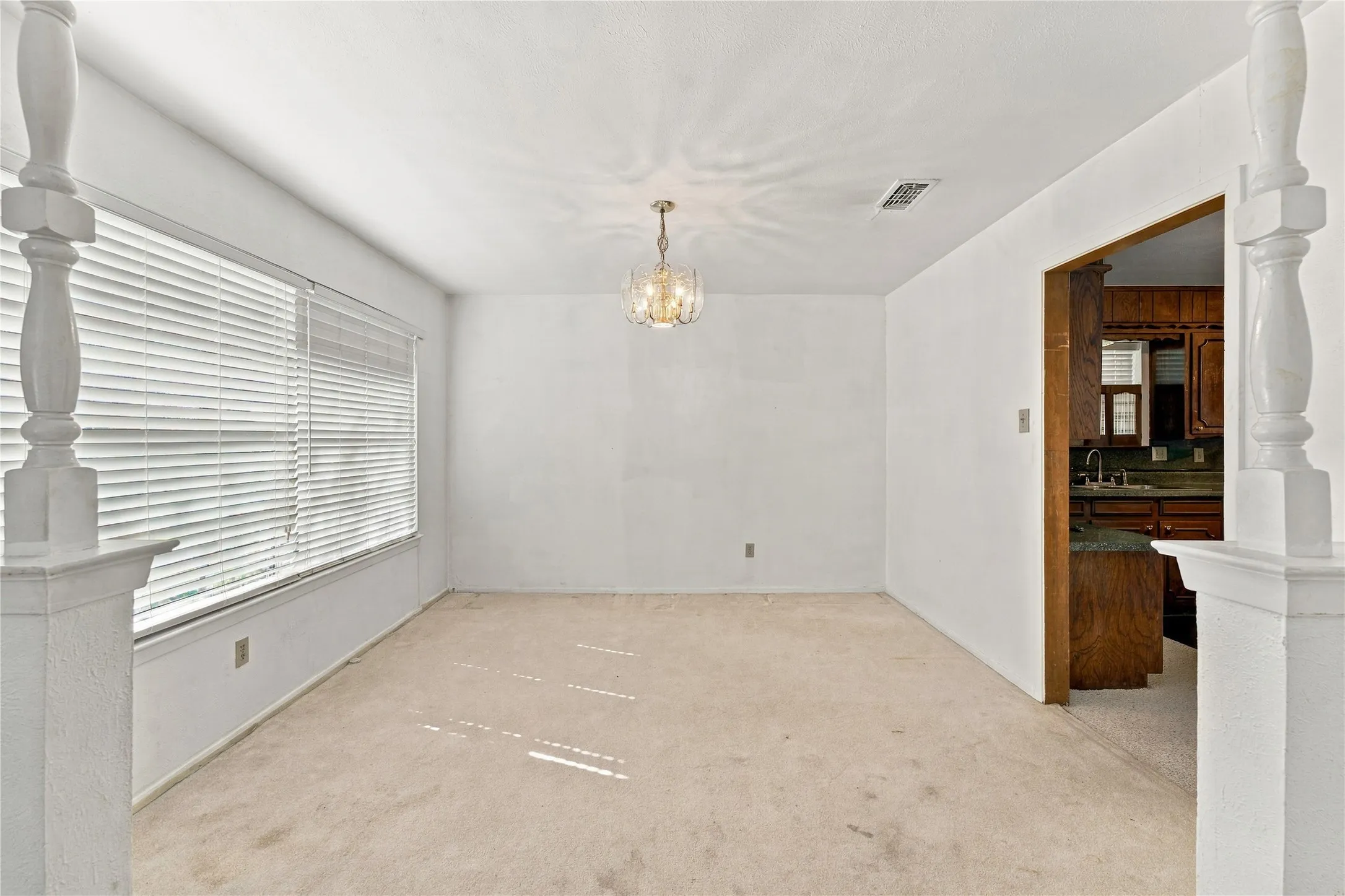 Spacious room with a large window, horizontal blinds, and a decorative ceiling light fixture
