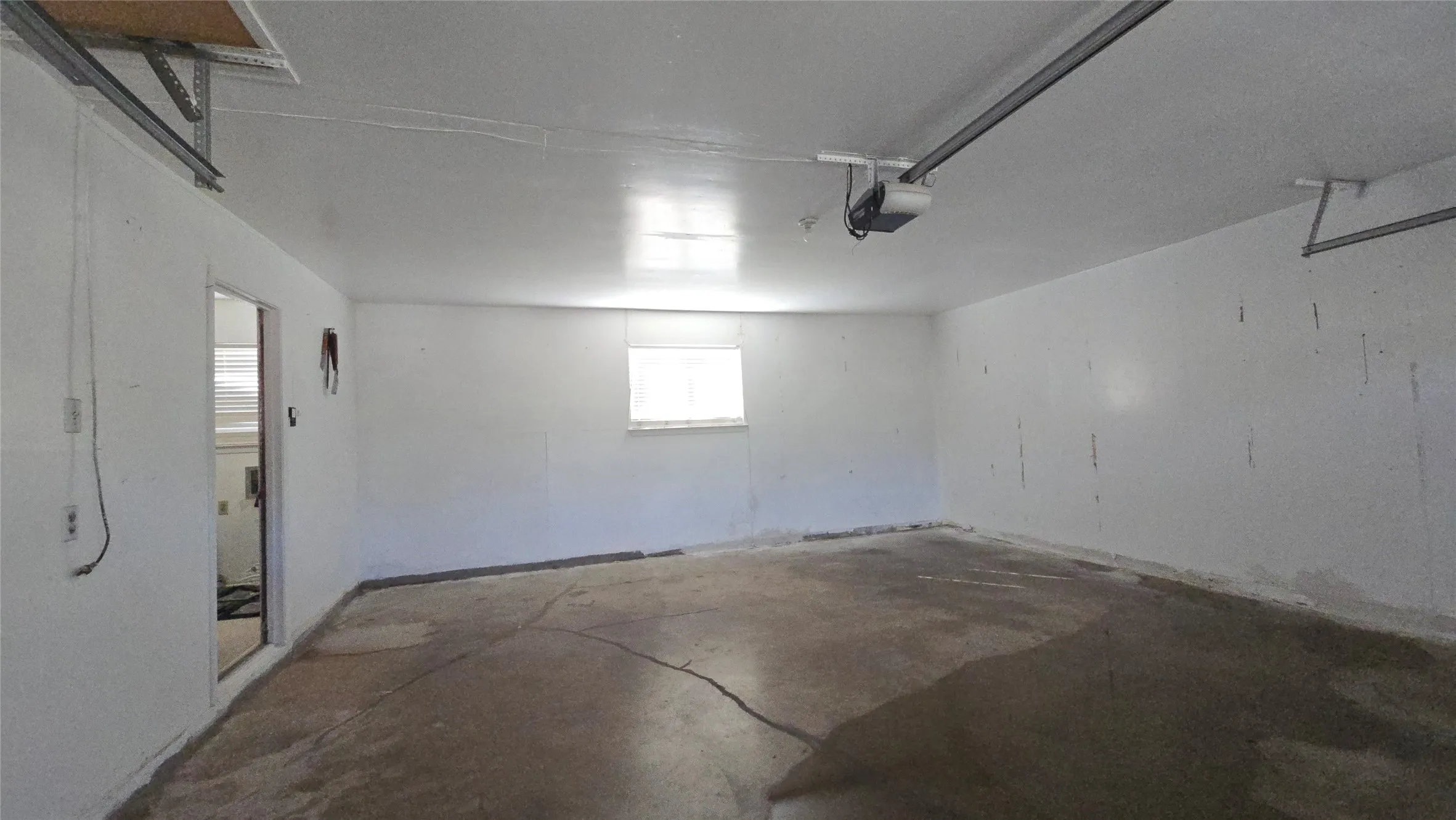 Single-car garage featuring a window, overhead garage door opener, and a door leading to interior space