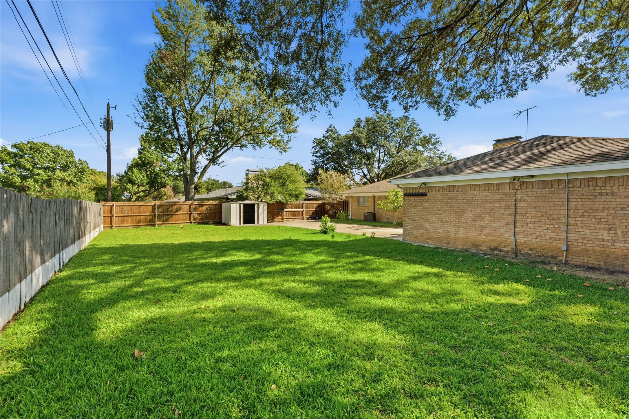 Expansive lawn area with a wood privacy fence and a detached storage shed