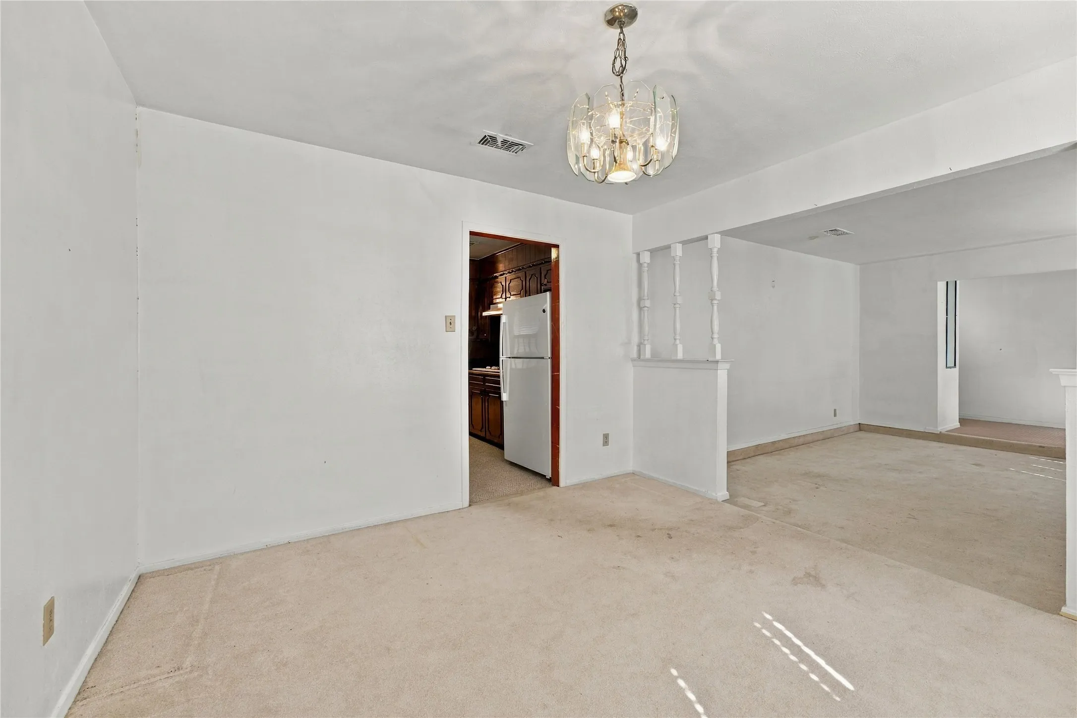 Recessed ceiling light, carpeted flooring, decorative chandelier, partial wall divider, wood-finish cabinetry
