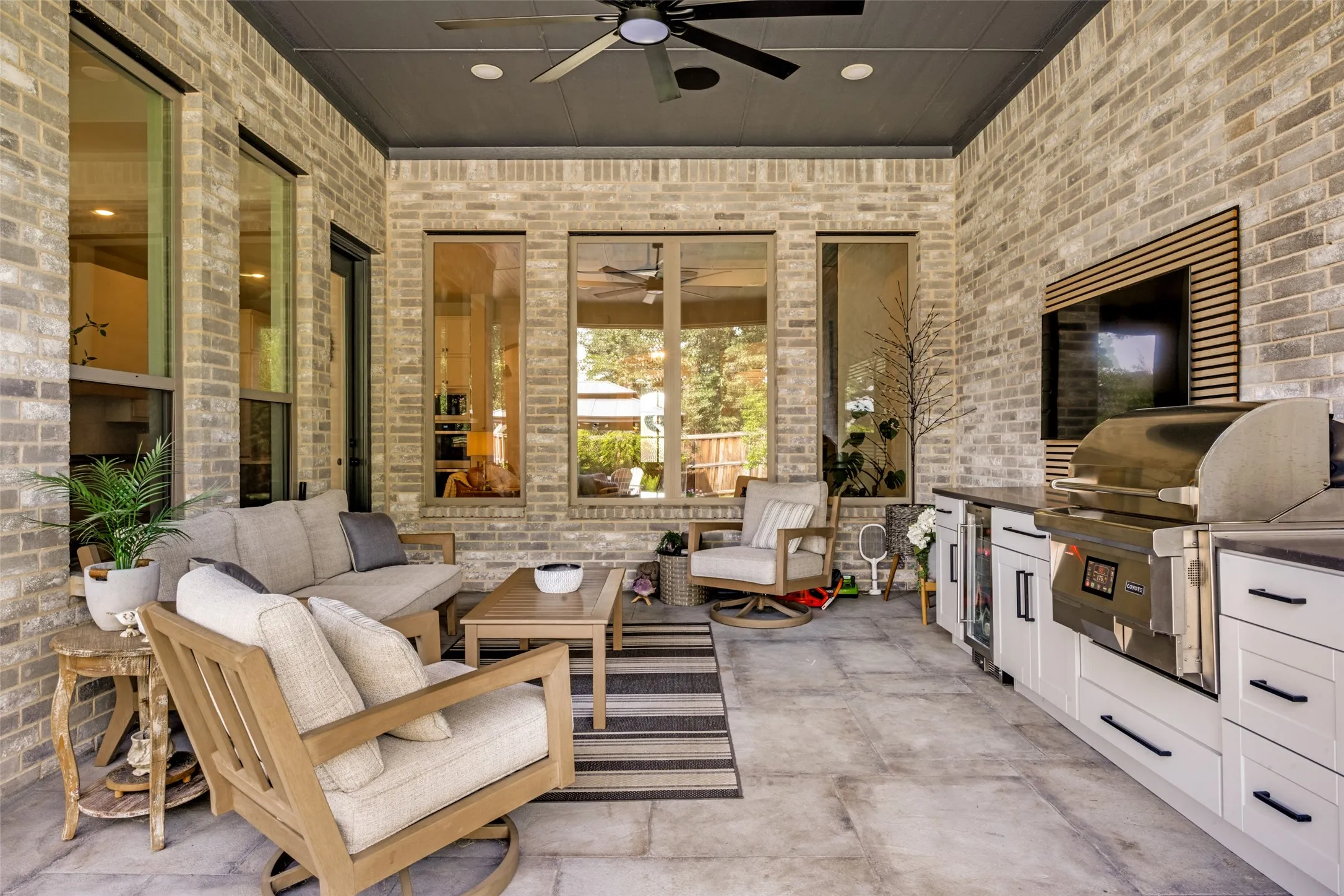 Covered patio with brick exterior, large format tile flooring, built-in outdoor kitchen, and ceiling fan