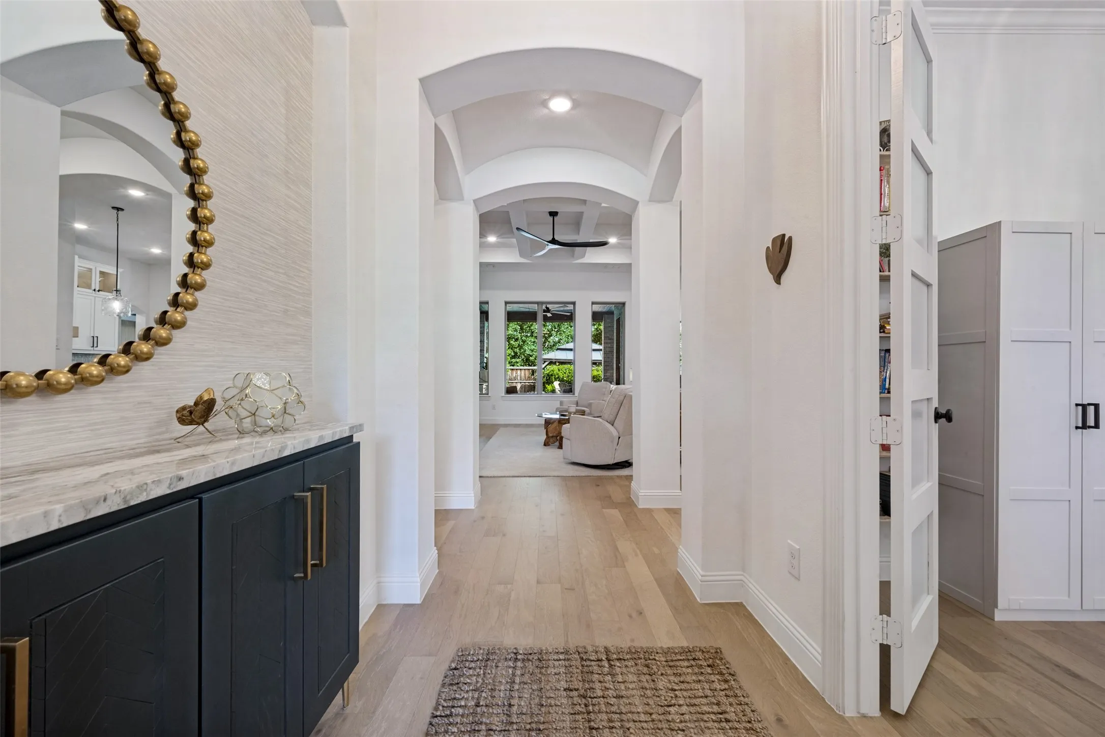 Arched doorways, wood floors, built-in cabinetry with stone countertop, and custom French doors