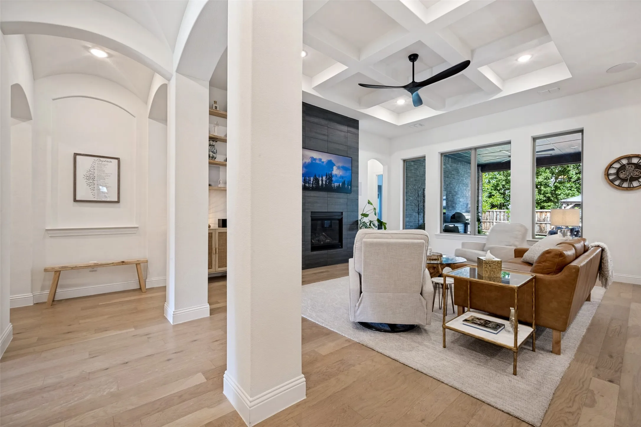 Light wood-finish flooring throughout, coffered ceiling, recessed lighting, and a modern ceiling fan