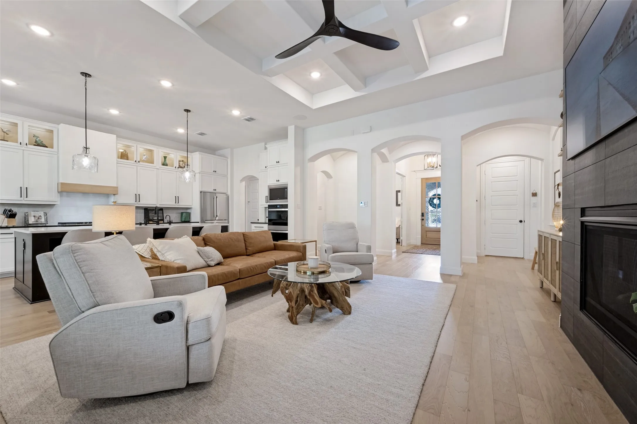 Open-concept living area featuring a coffered ceiling, recessed lighting, and wood-finish flooring