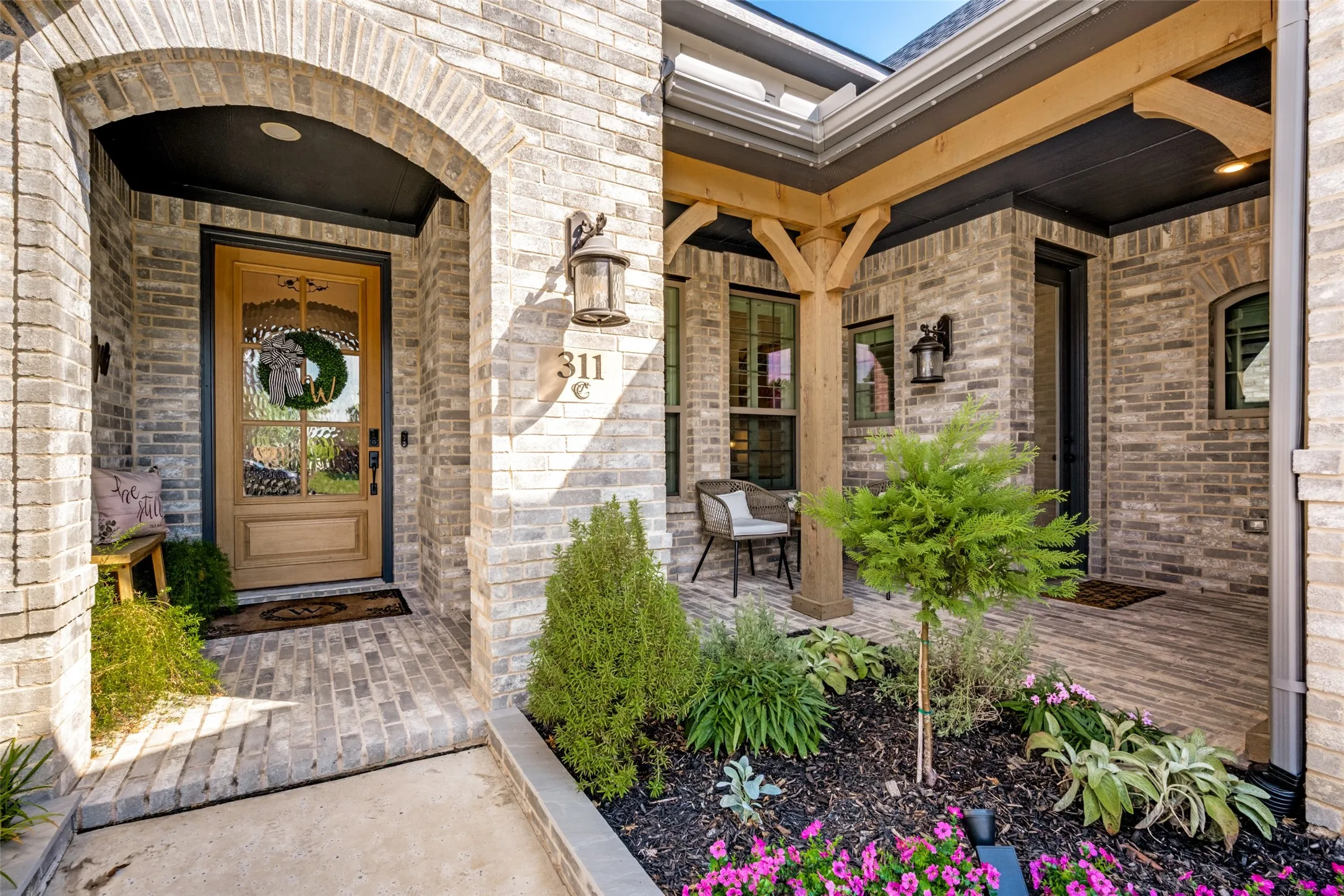 Brick exterior with a wooden front door under an arched entry. Accented by jellyfish lights.