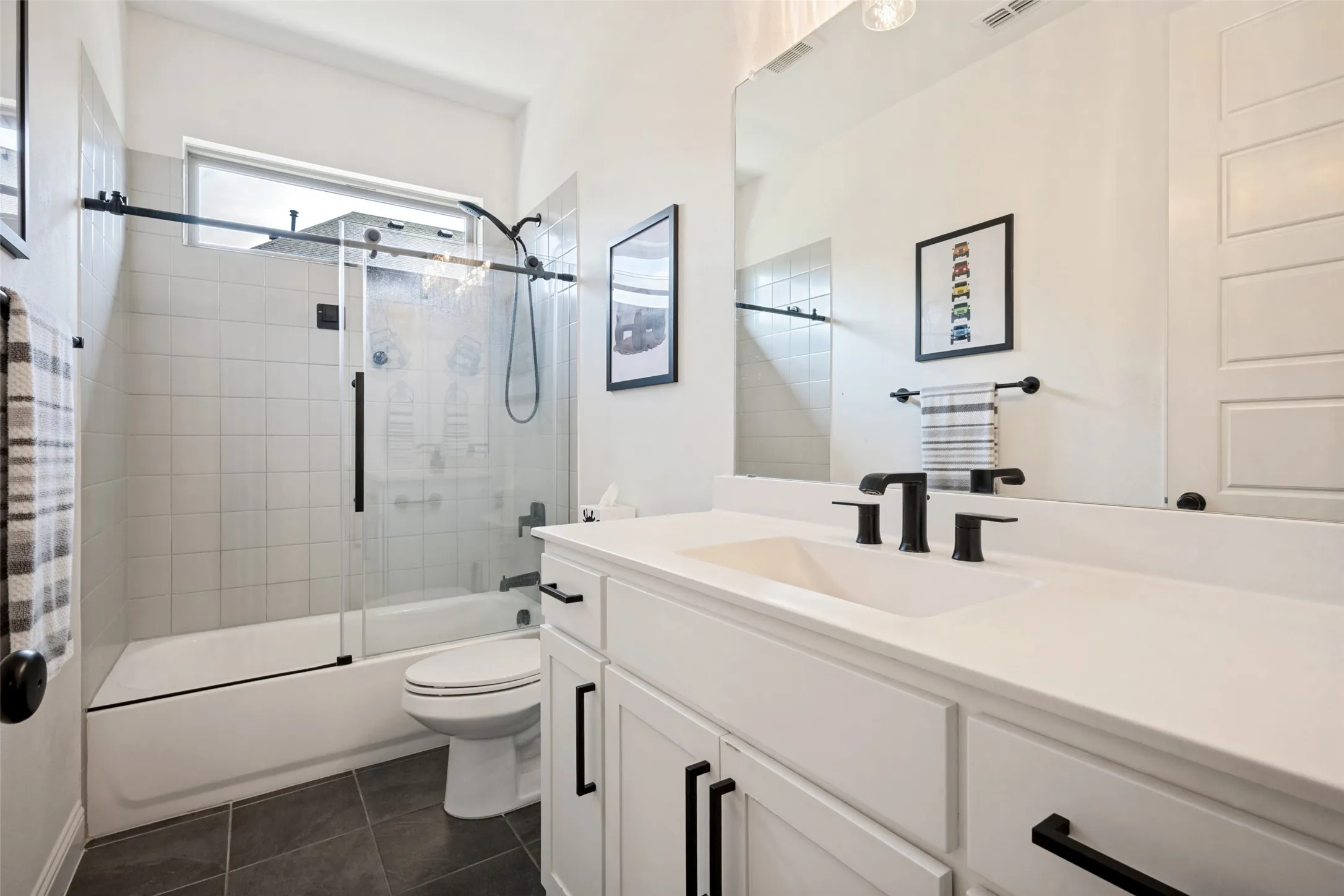 White vanity with integrated sink, matte black fixtures, and a large frameless mirror