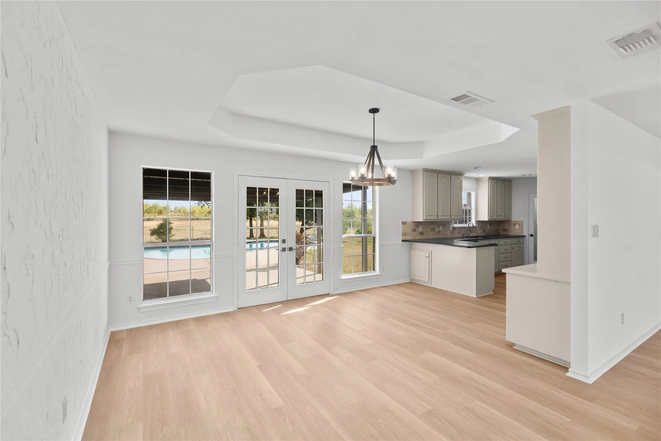The spacious layout lets the kitchen, dining, and living areas flow together beautifully, with French doors and oversized windows bringing the outdoors in.