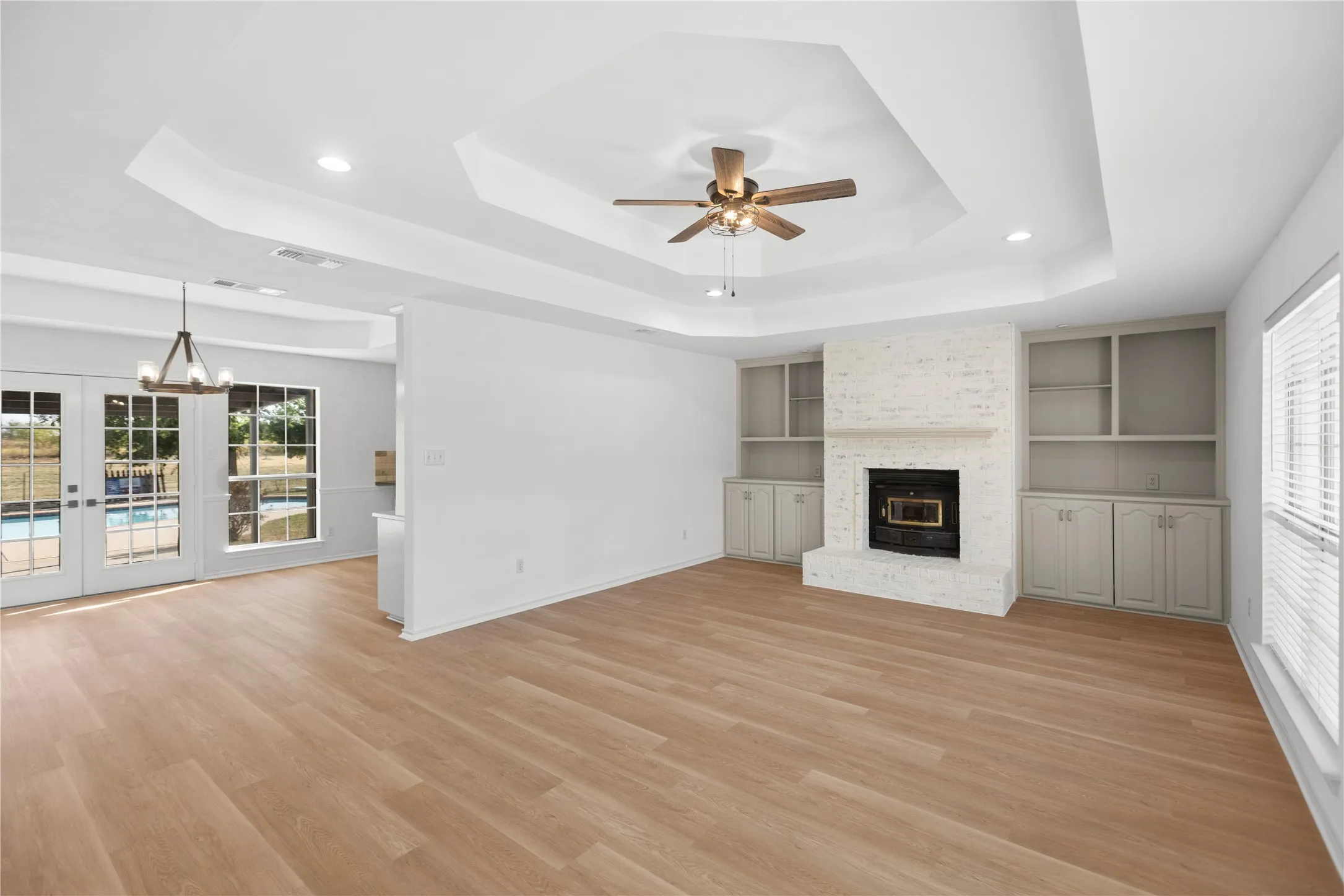 Look at all that room! New LVP flooring, fresh white walls, custom built-ins, and a charming fireplace create an inviting gathering space.
