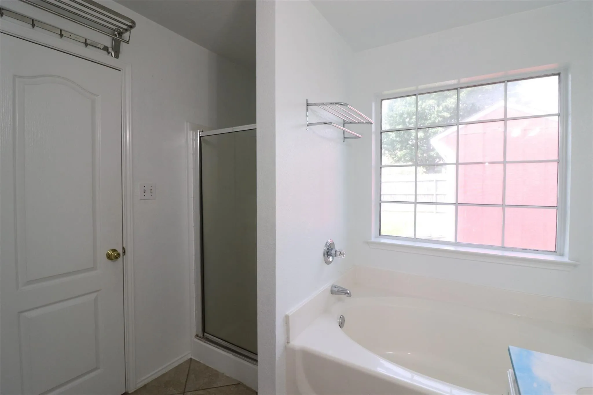 Built-in bathtub with chrome fixtures, a window with gridded panes, and a separate shower enclosure