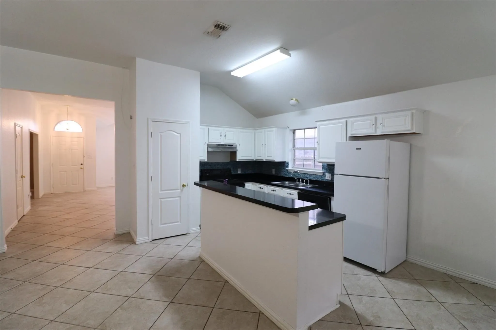Kitchen featuring black countertops, white cabinetry, and tile flooring