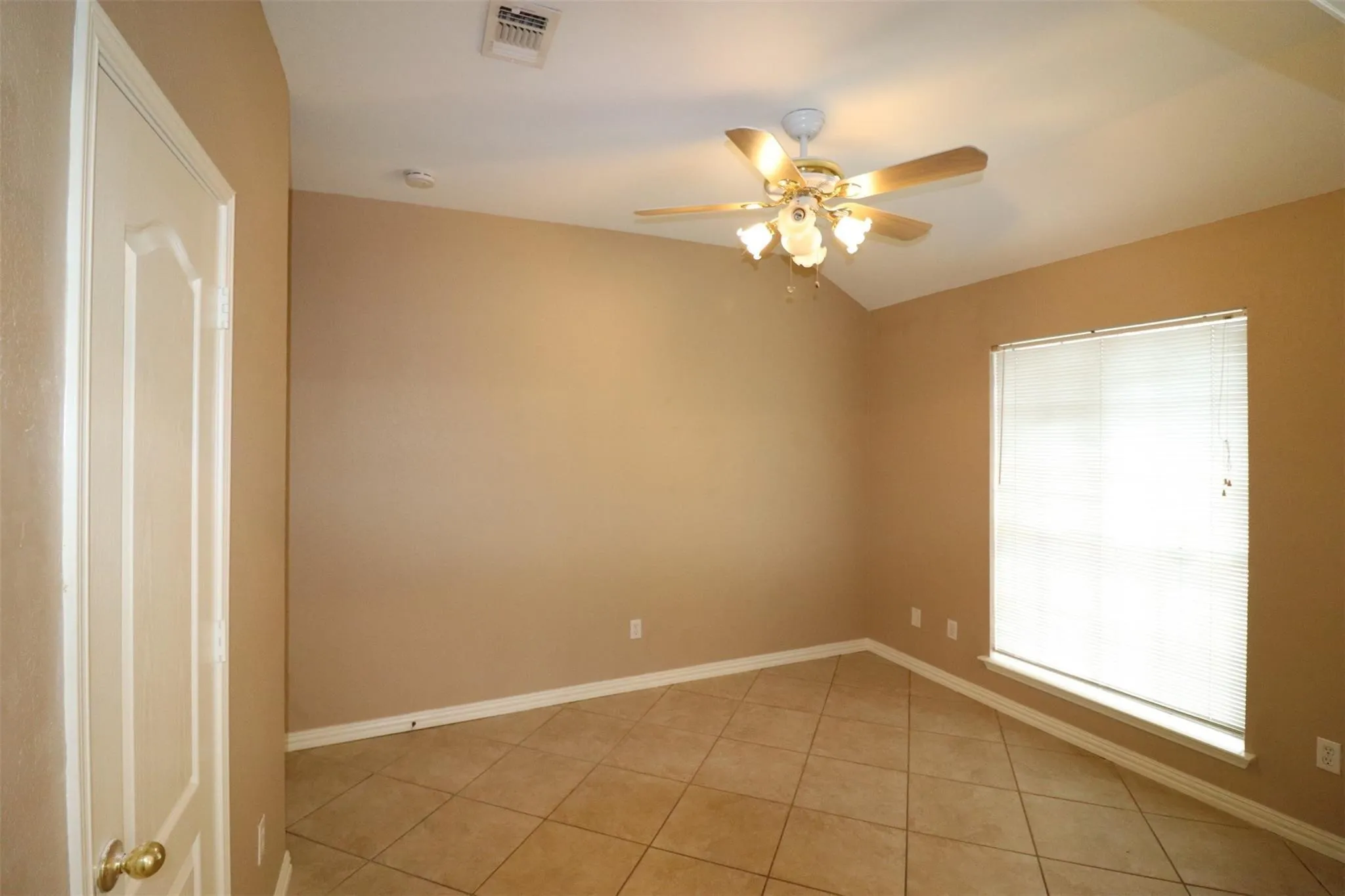 Vaulted ceiling with a ceiling fan light fixture, ceramic tile flooring, and a window with blinds