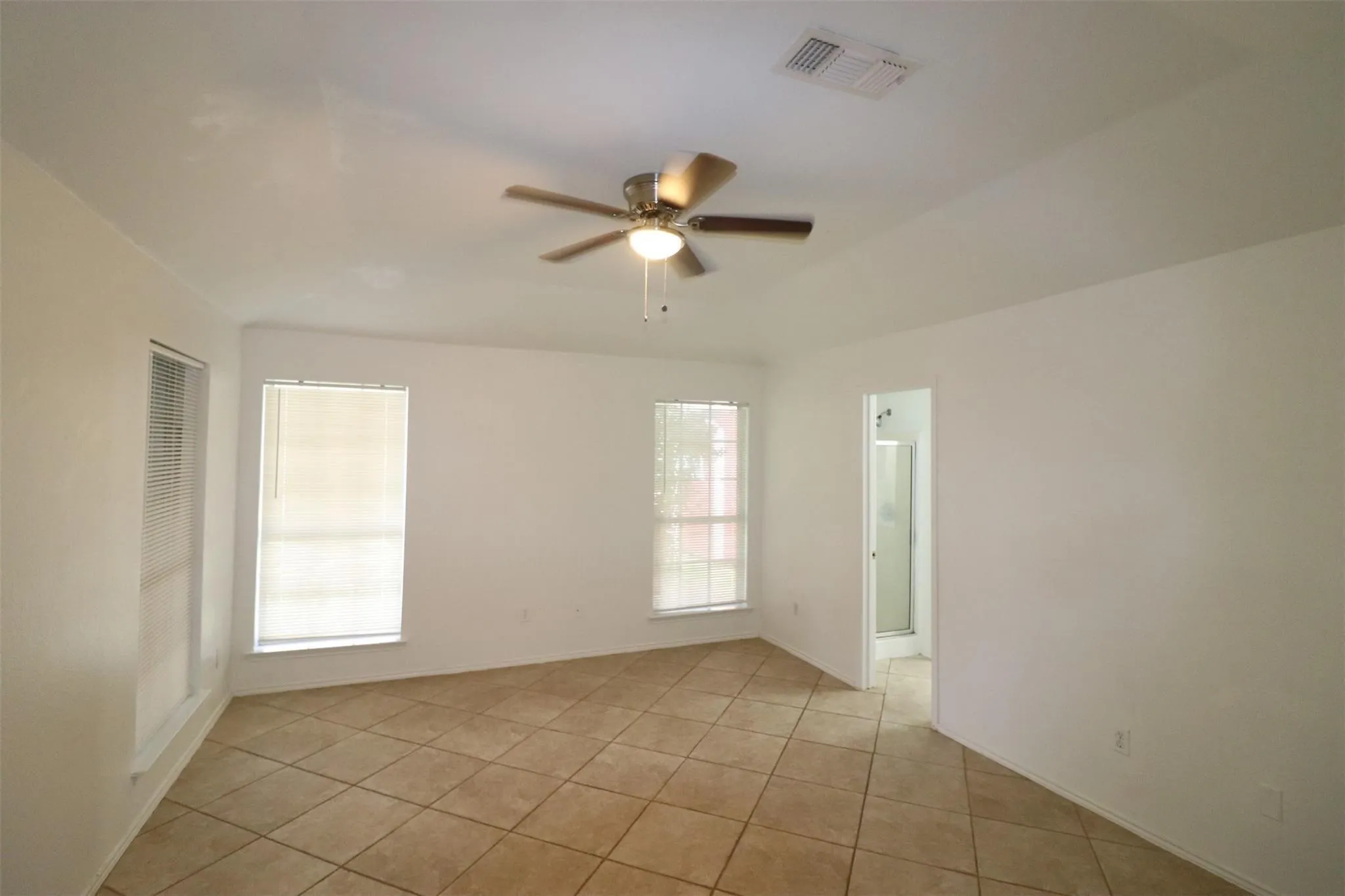 Vaulted ceiling with an integrated ceiling fan, ceramic tile flooring, and multiple windows