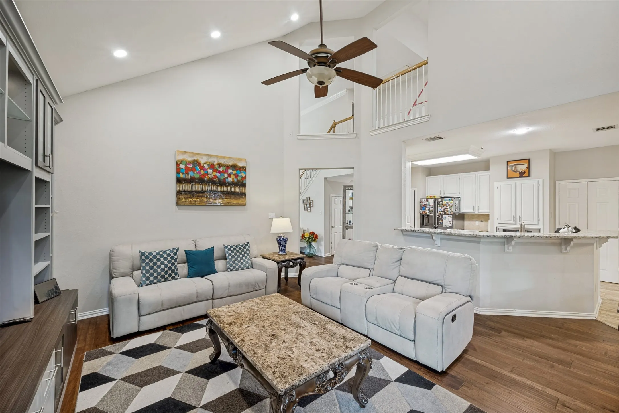 Vaulted ceiling with recessed lighting, wood-finish flooring, built-in cabinetry, and a ceiling fan