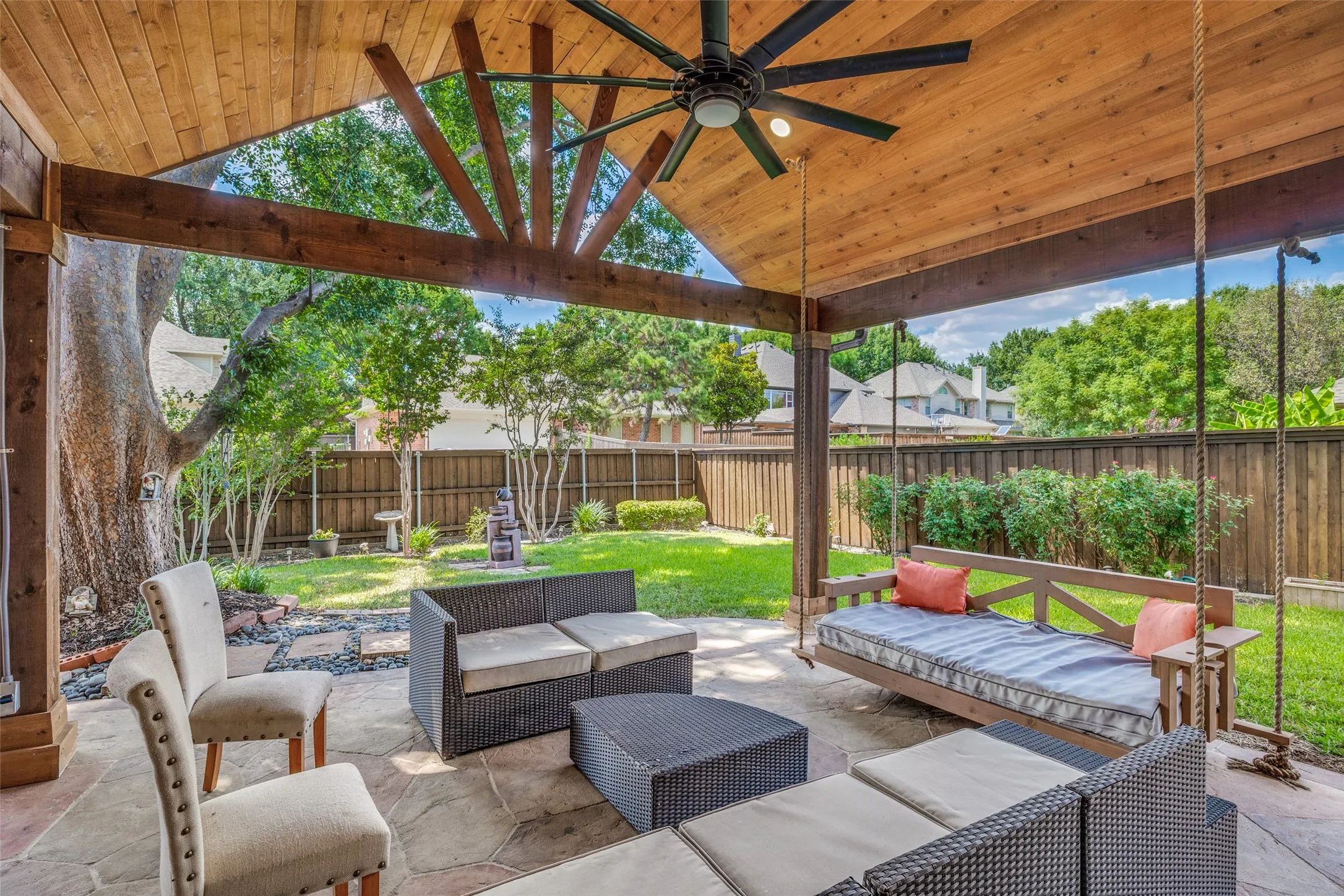 Expansive covered patio with a vaulted wood-paneled ceiling, exposed beam structure, and a ceiling fan