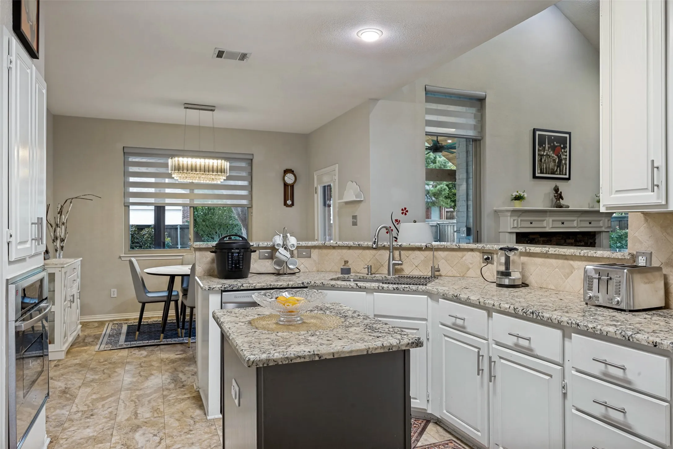 Kitchen featuring granite countertops, a tile backsplash, white cabinetry, a built-in oven, and a vaulted ceiling