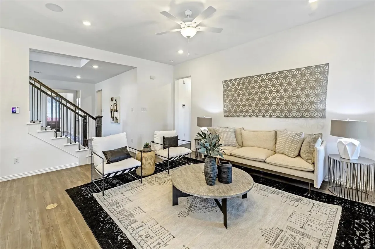 Open-concept living area featuring wood-finish flooring, recessed lighting, a ceiling fan, and a staircase with metal balusters
