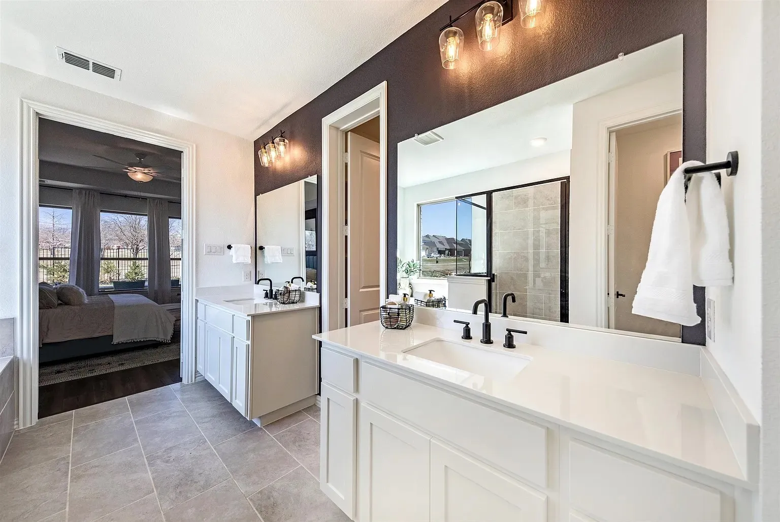 Dual vanities with white cabinetry, integrated sinks, and dark fixtures
