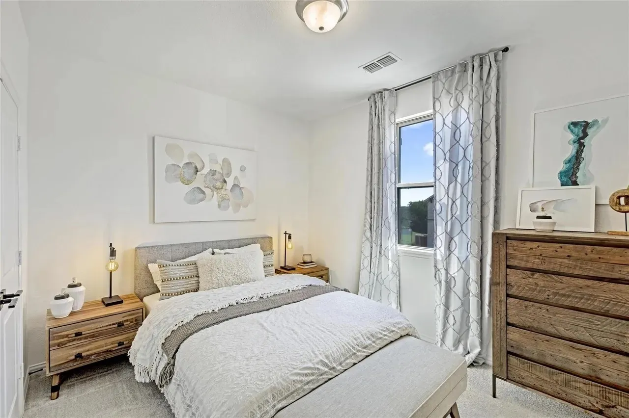 Window with roller shade and decorative curtains, flush mount ceiling light fixture, wood-finish flooring, and white walls