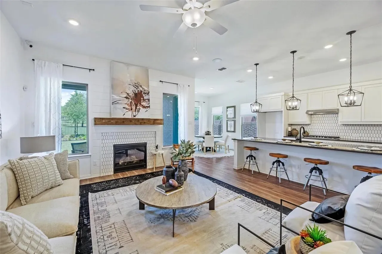 Open-concept living space featuring wood-finish flooring, a contemporary fireplace with a wood mantle, recessed lighting, and a ceiling fan