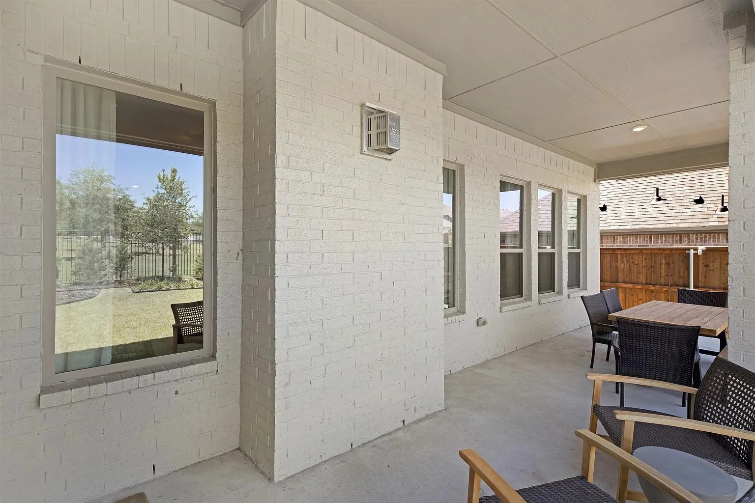 Expansive covered patio with concrete flooring, recessed lighting, and painted brick exterior walls