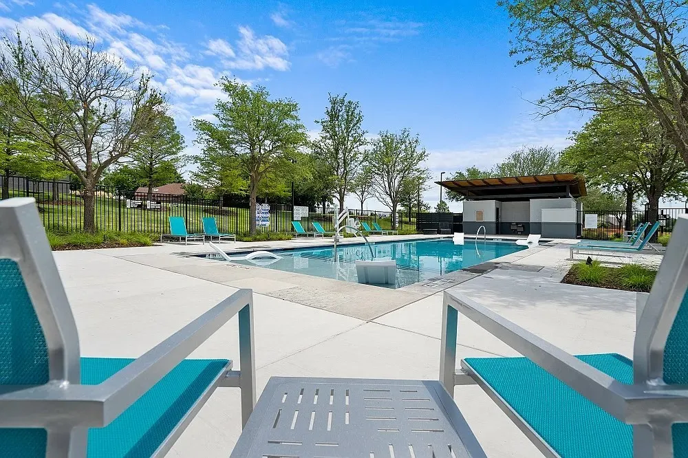 Resort-style pool with integrated lounge seating, expansive concrete decking, and a shaded outdoor structure